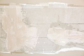 A wall with horizontal panels covered in patchy, off-white plaster or spackle, creating a textured, unfinished surface.