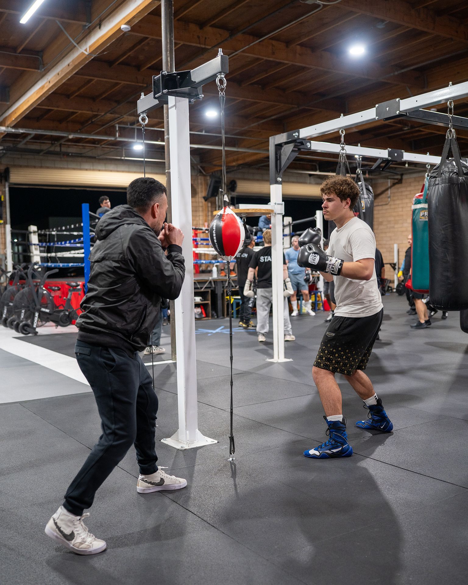 Inside a boxing ring, two figures train in a dimly lit gym.