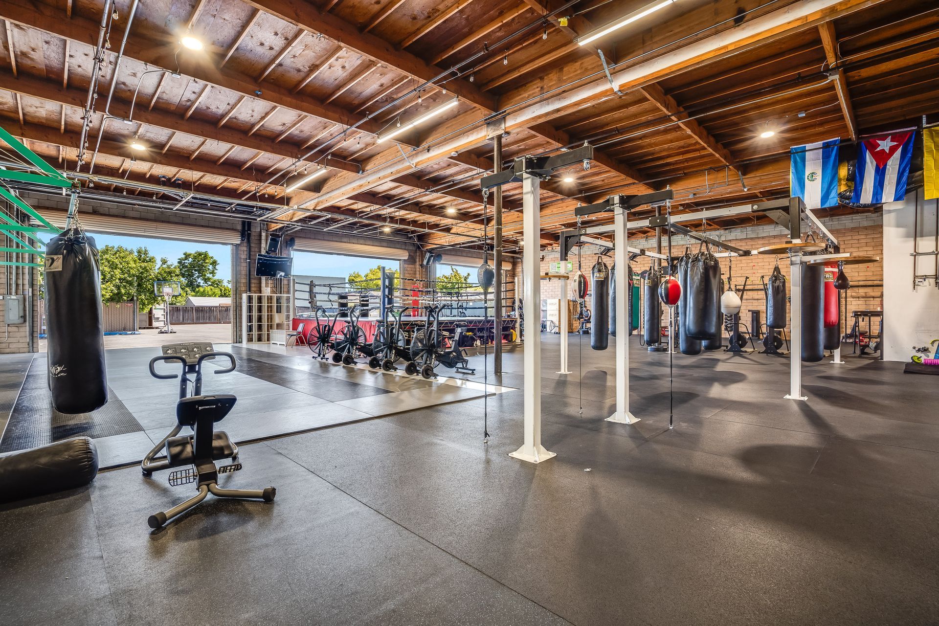 Gym interior with punching bags, weights, and open garage doors.