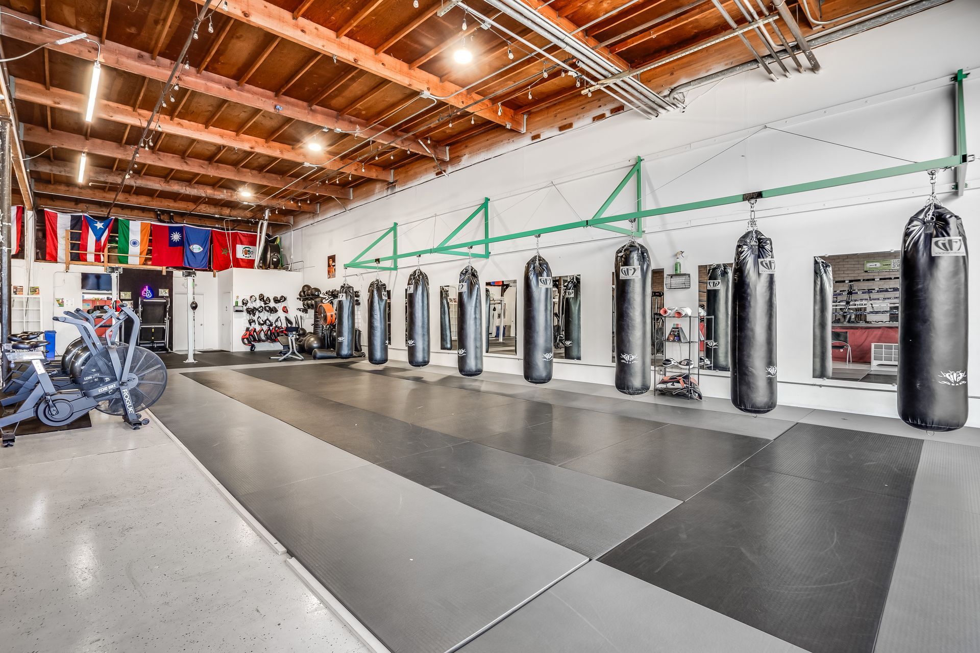 Boxing gym with punching bags hanging, equipment, and flags.