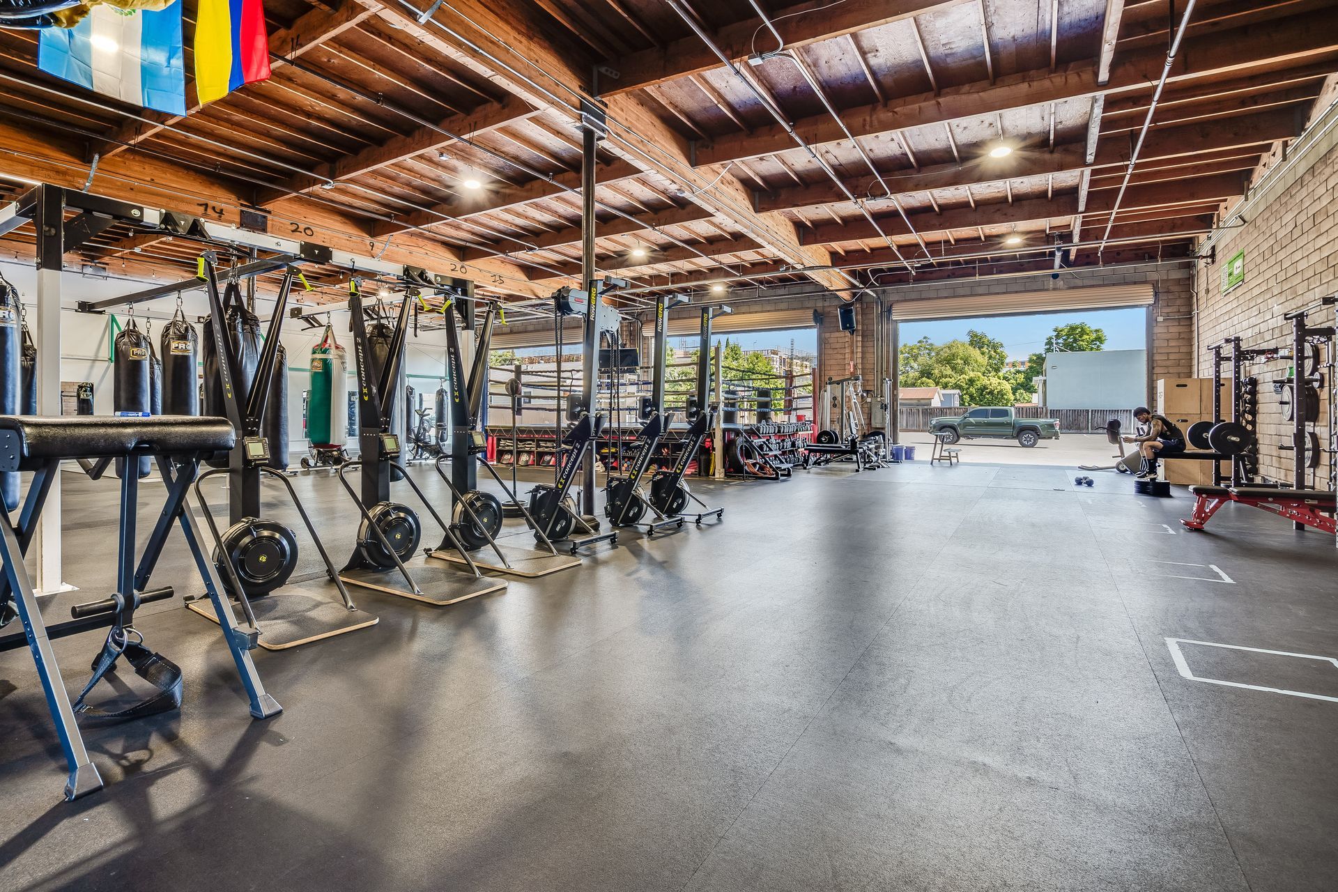 Gym interior with workout equipment, open garage door, and flags.