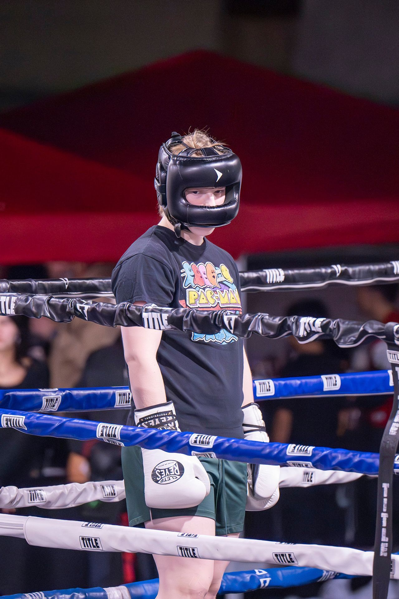 Boxer in a ring, wearing a helmet and gloves, standing.