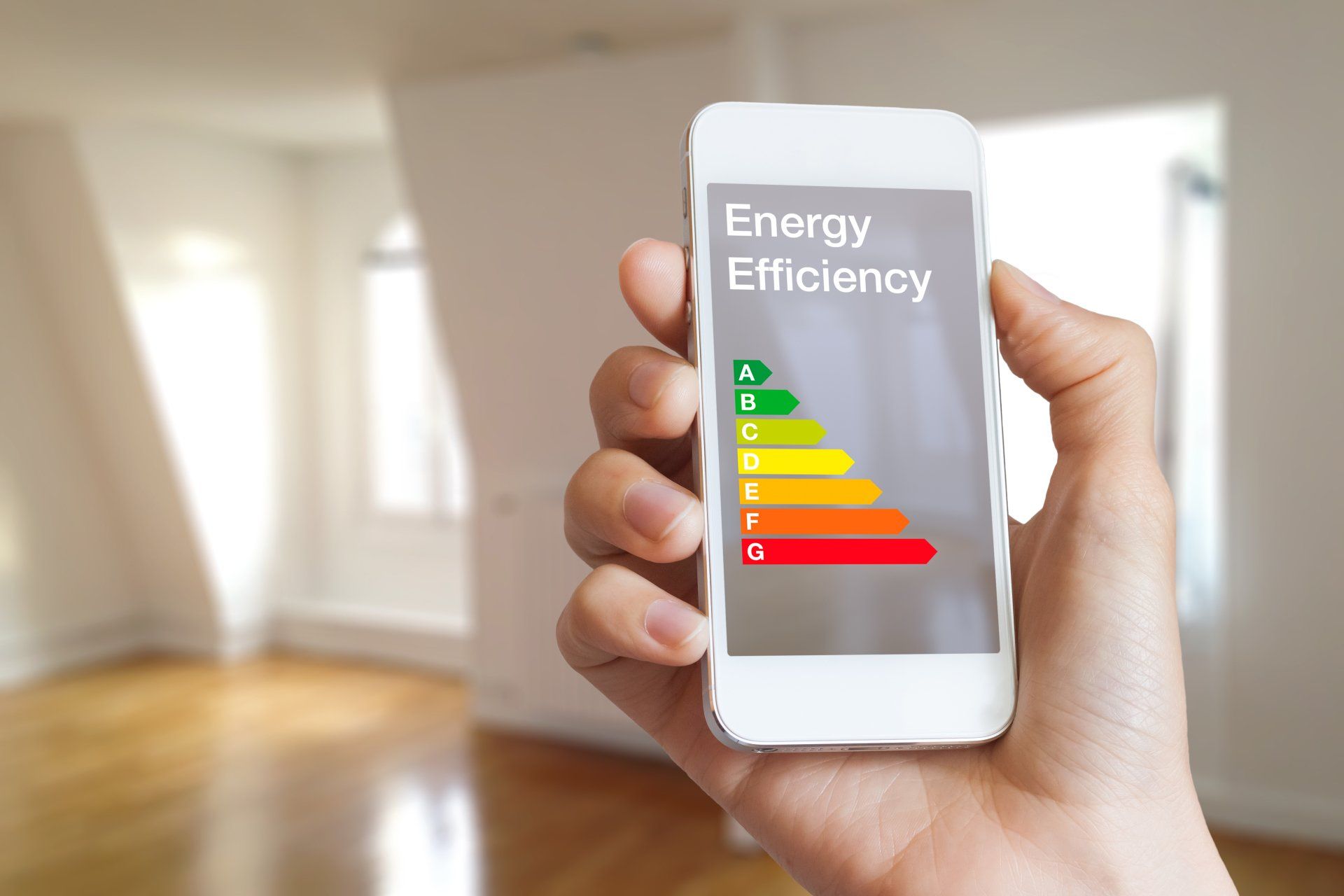 A person is holding a cell phone with an energy efficiency rating on the screen.