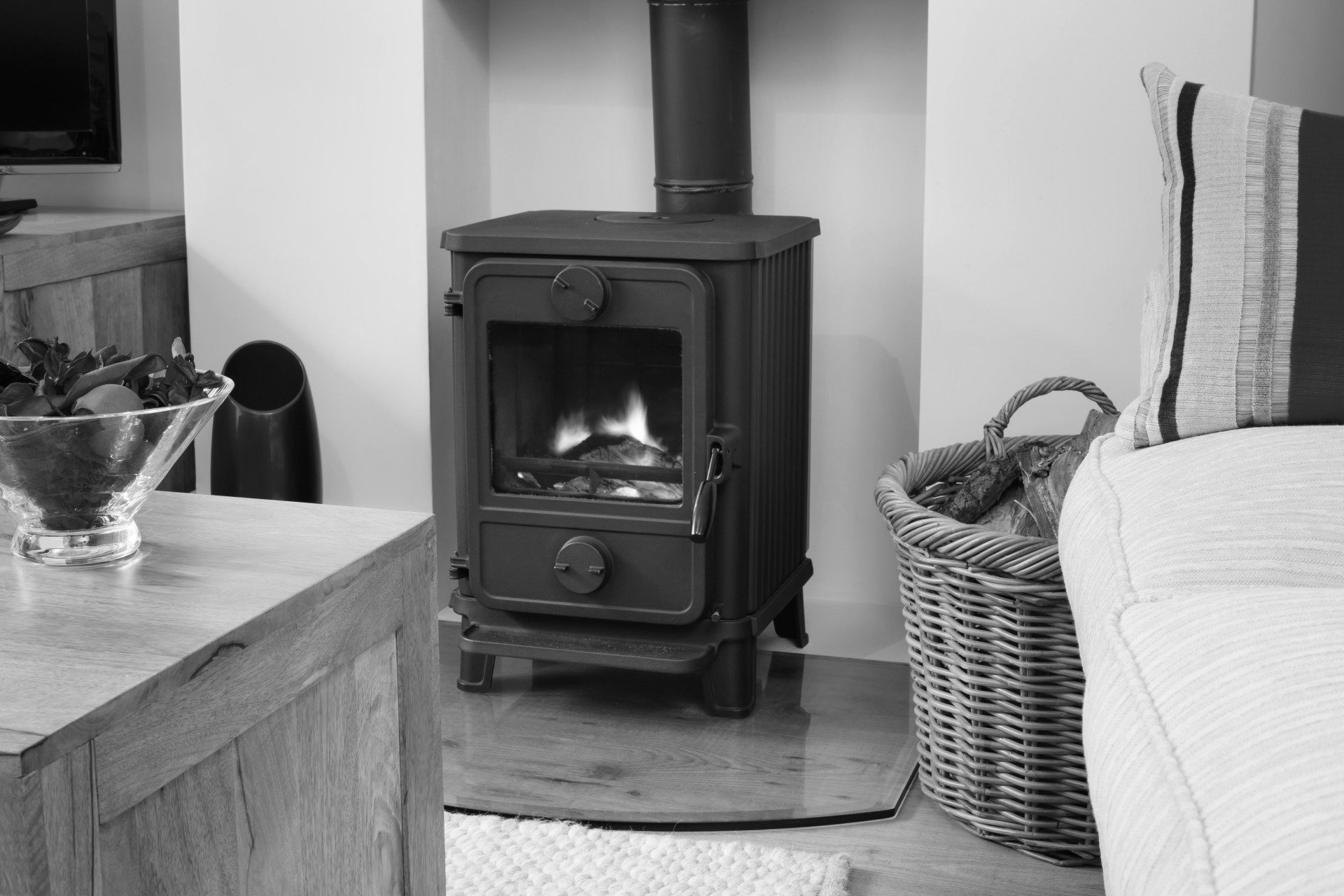 A black and white photo of a wood stove in a living room.