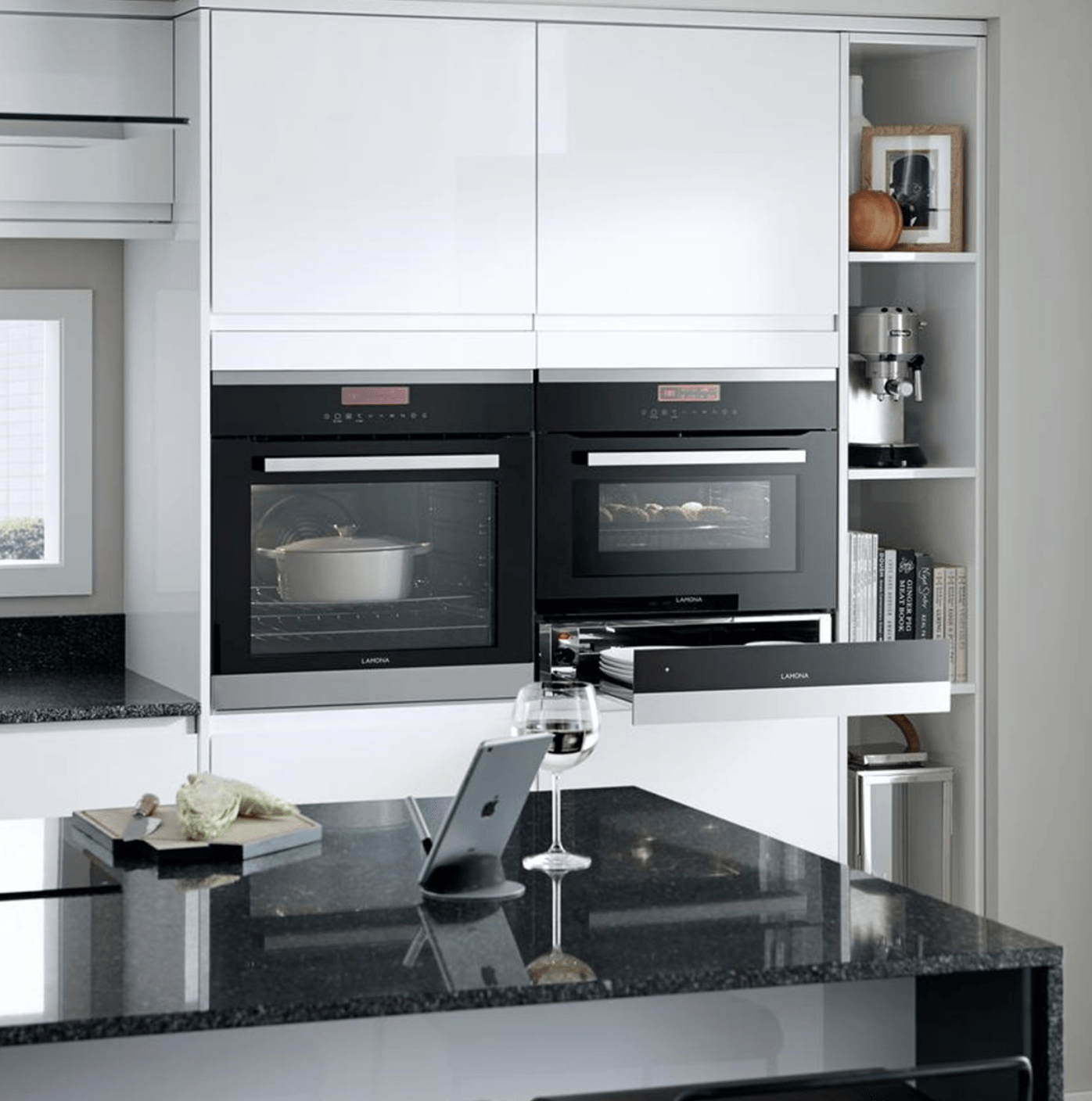 A kitchen with two ovens and a glass of wine