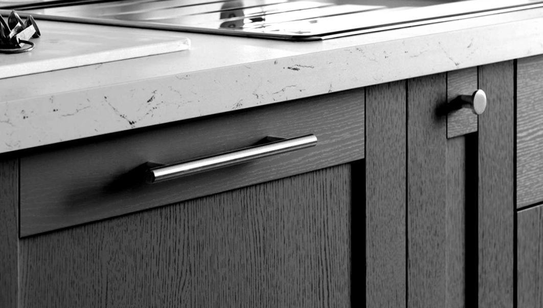 A black and white photo of a kitchen counter with wooden cabinets and a stove top oven.
