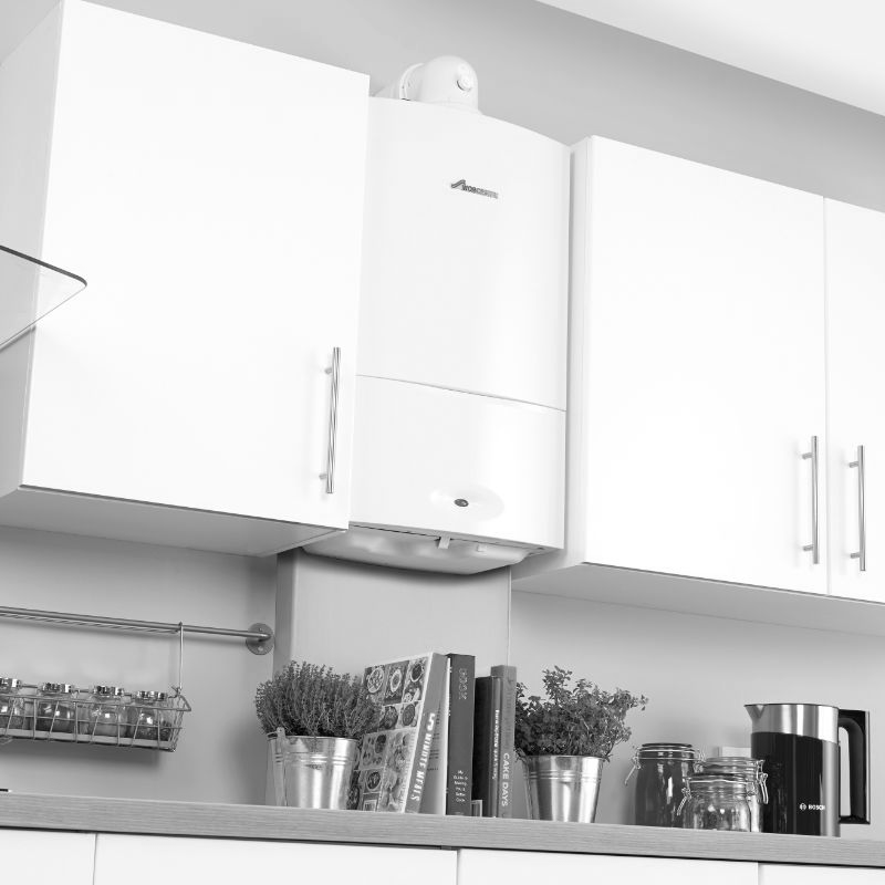 A black and white photo of a kitchen with white cabinets and a stove.