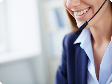 A smiling professional in a business suit and headset, providing customer support in an office setting.