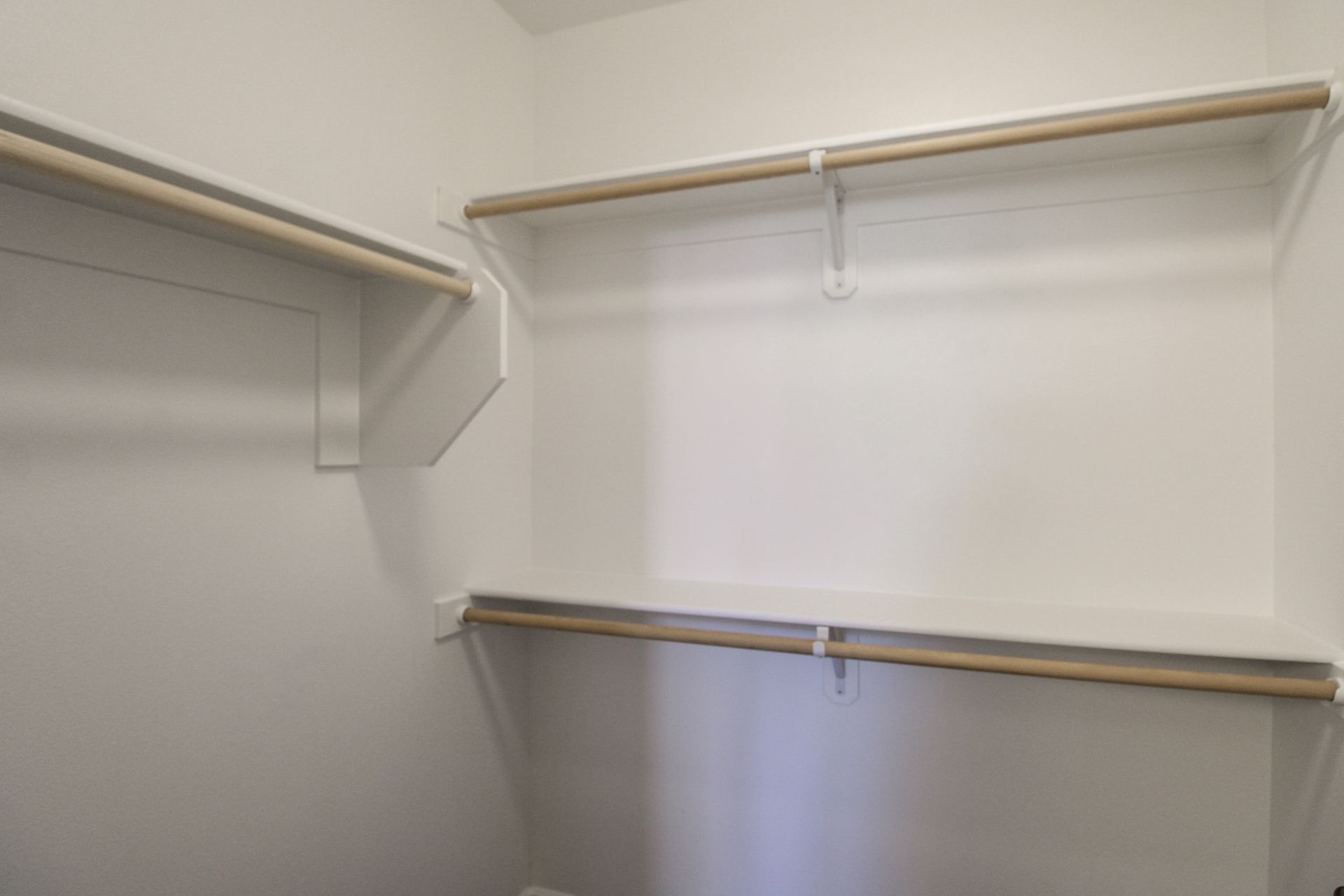 An empty walk in closet with shelves and clothes racks.