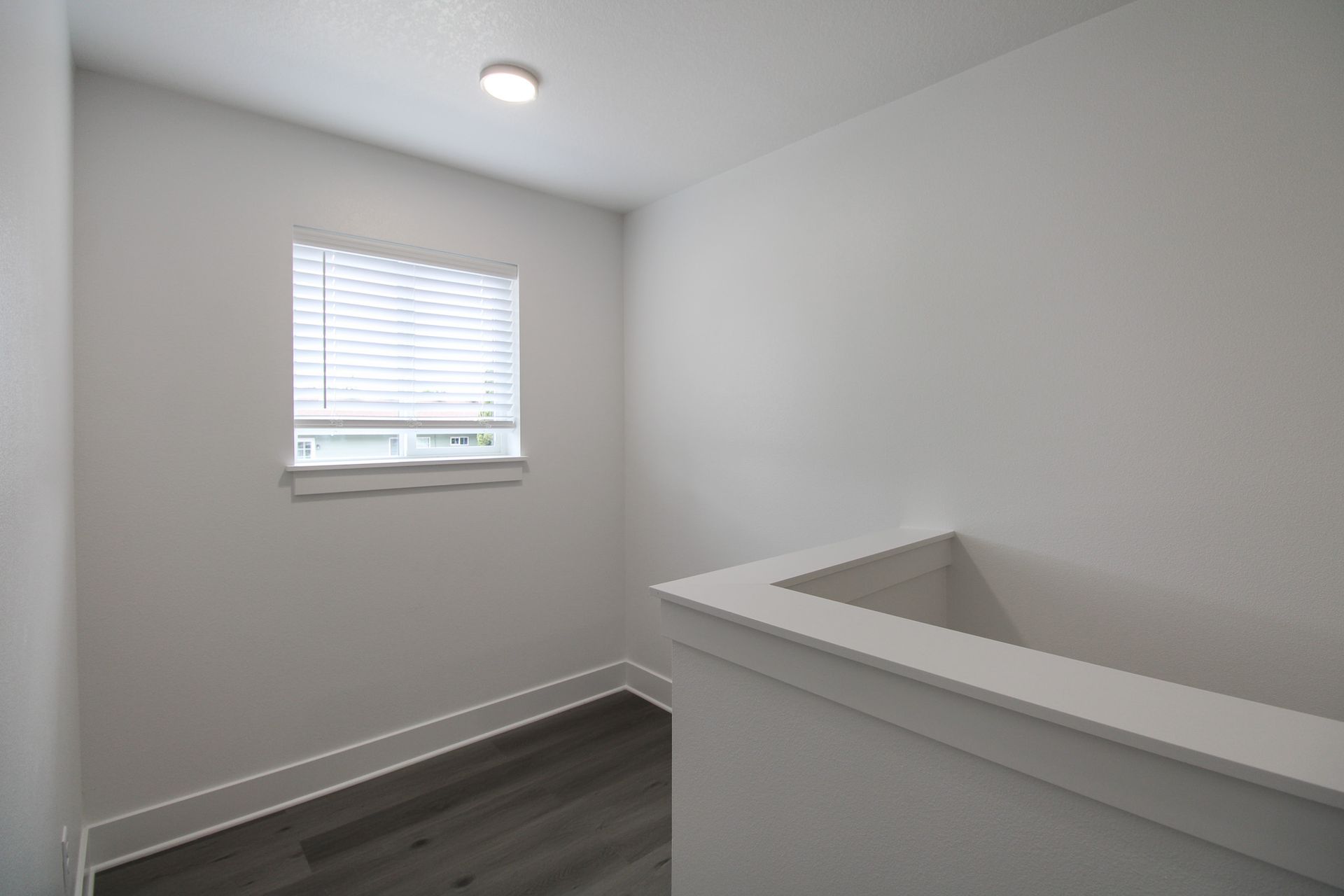 An empty room with a window and a railing.