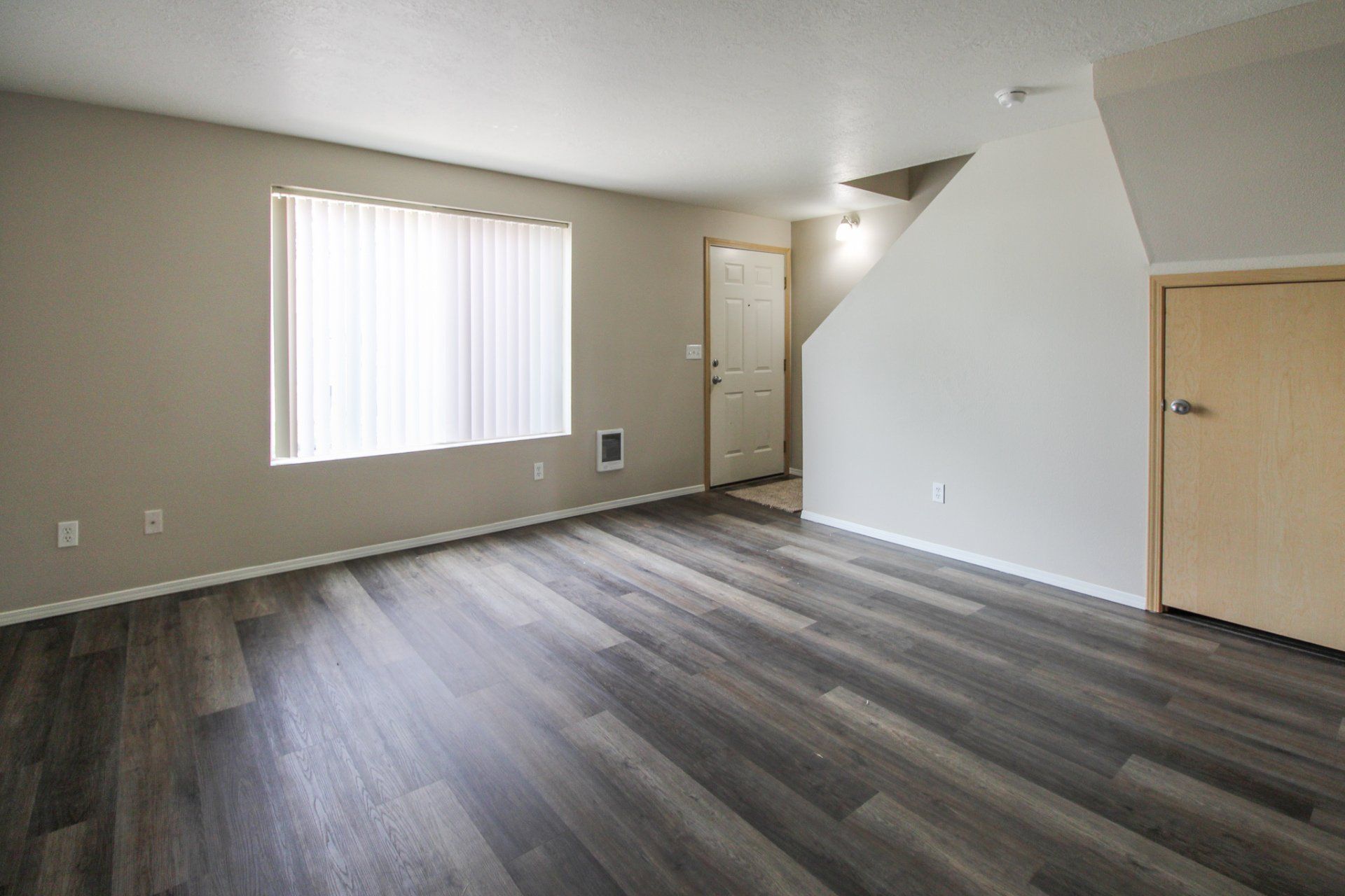 An empty living room with hardwood floors and a window.