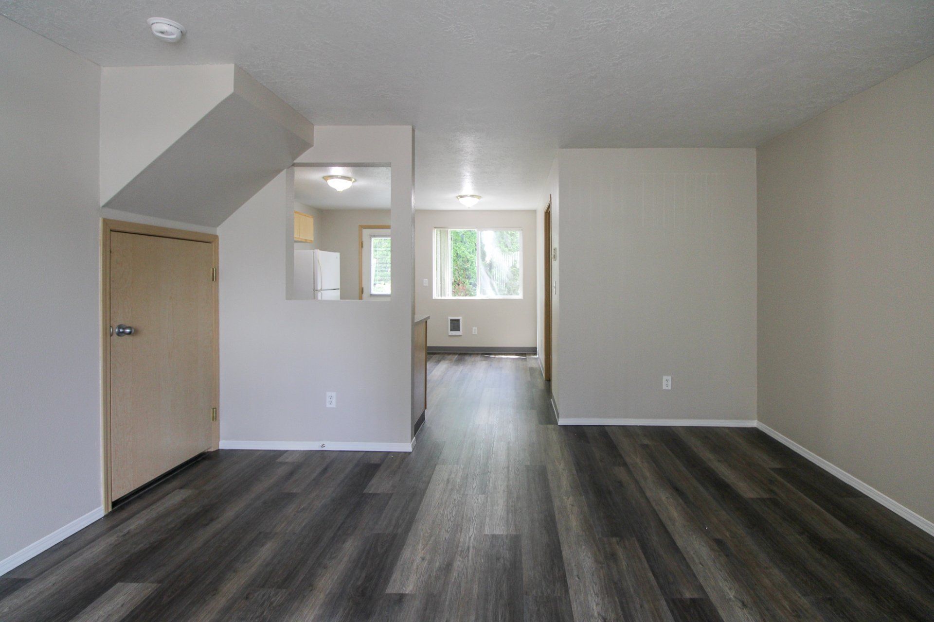 An empty living room with hardwood floors and white walls.