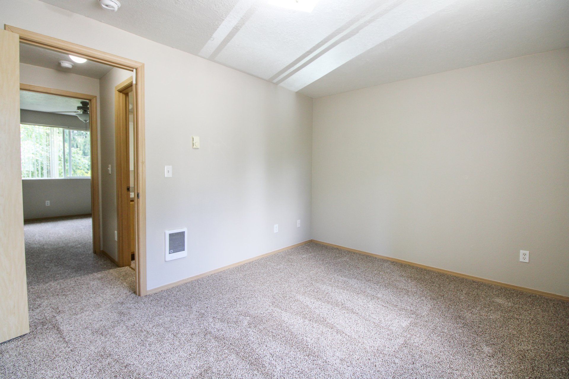 An empty bedroom with a carpeted floor and a ceiling fan.