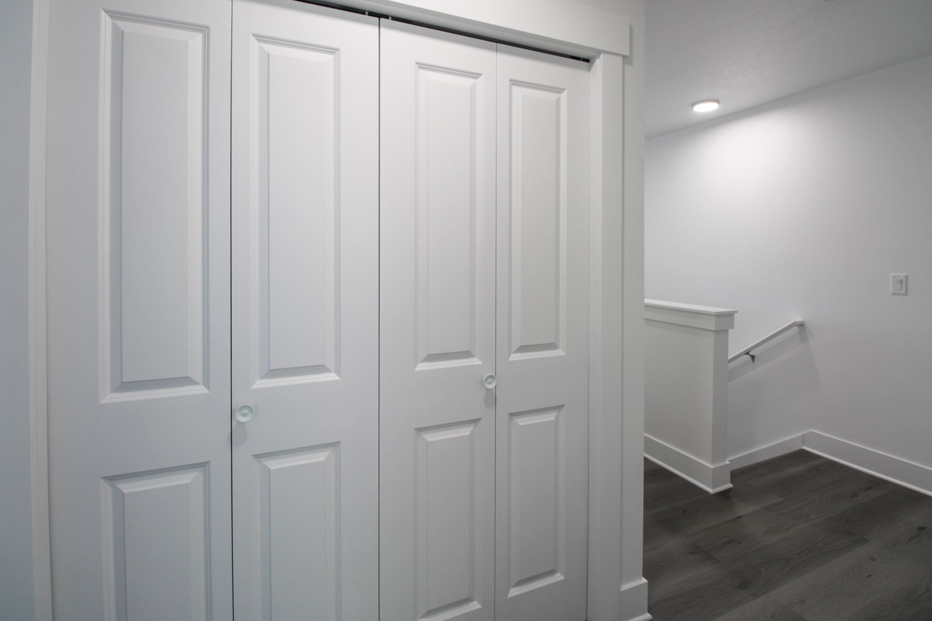 A hallway with white doors and a staircase in the background.