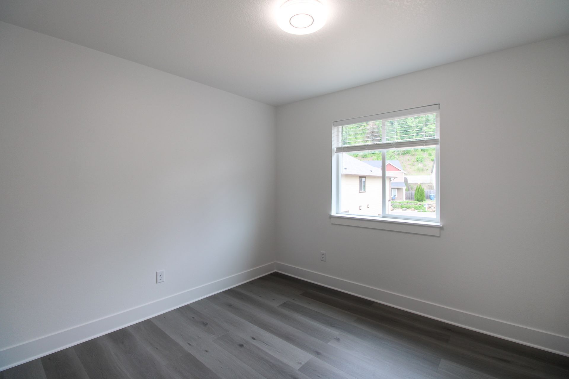 An empty bedroom with hardwood floors and a window.