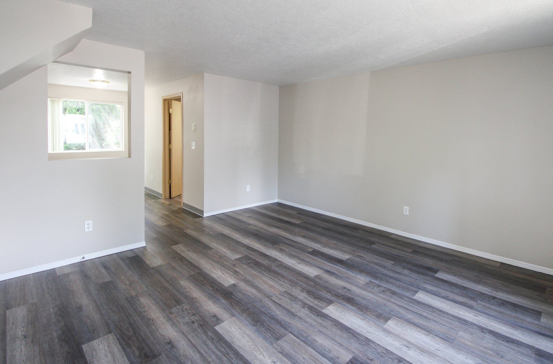 An empty living room with hardwood floors and white walls.