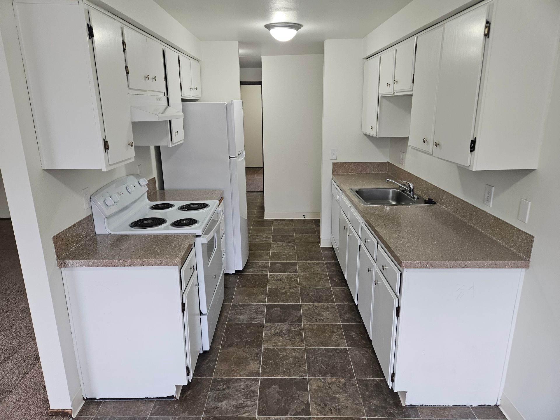 A kitchen with white cabinets a stove a refrigerator and a sink