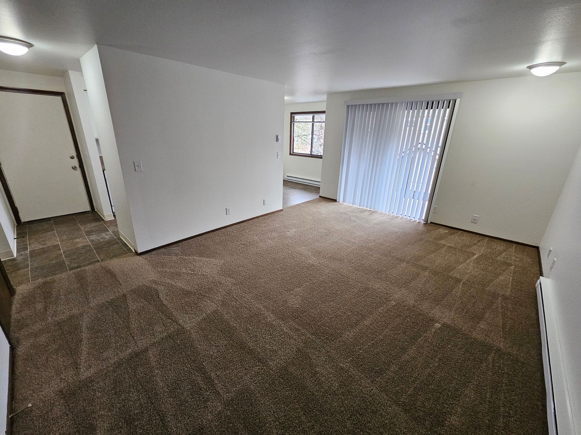 A living room with a sliding glass door and a window.
