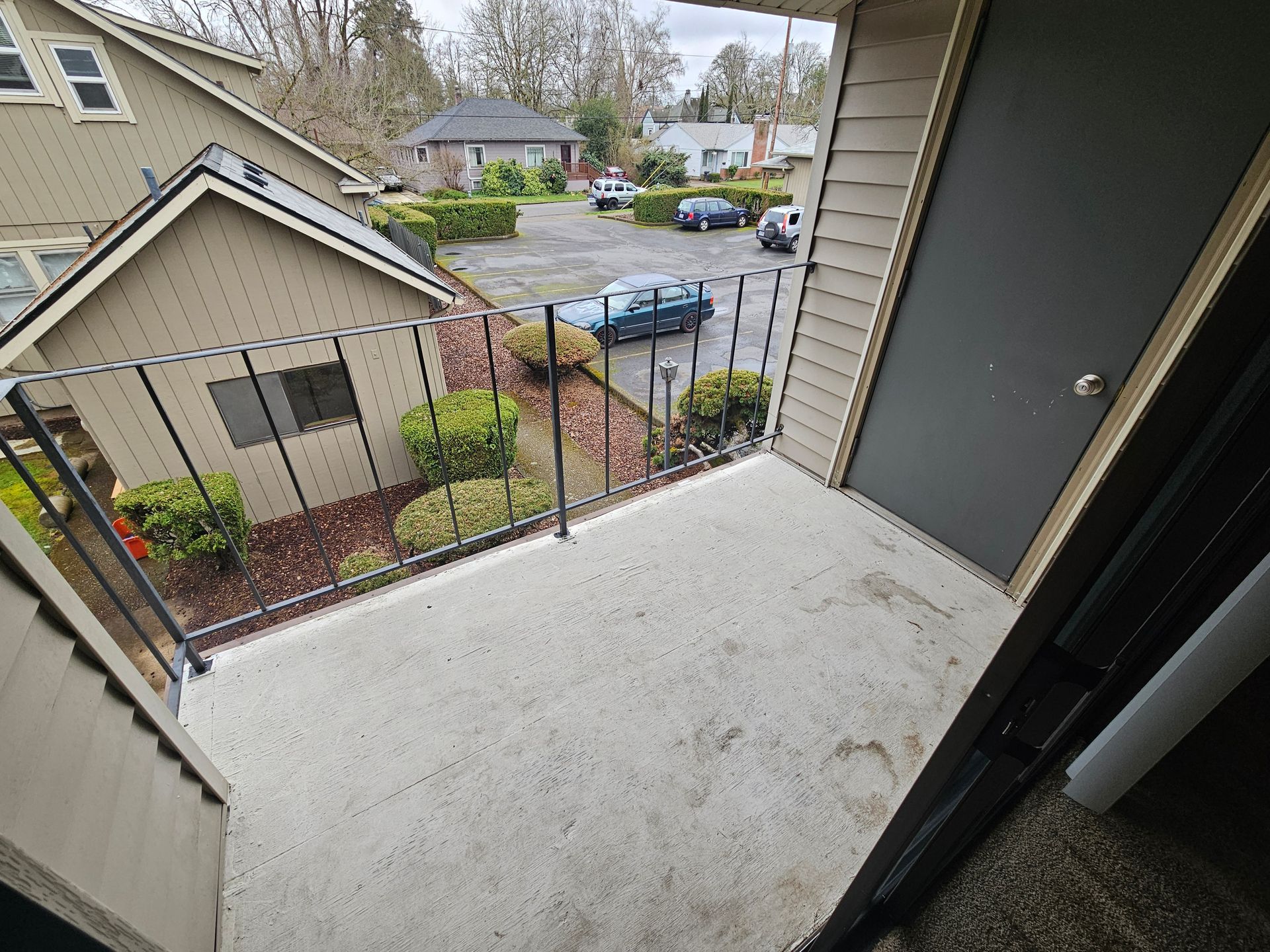 A balcony with a view of a house and a parking lot