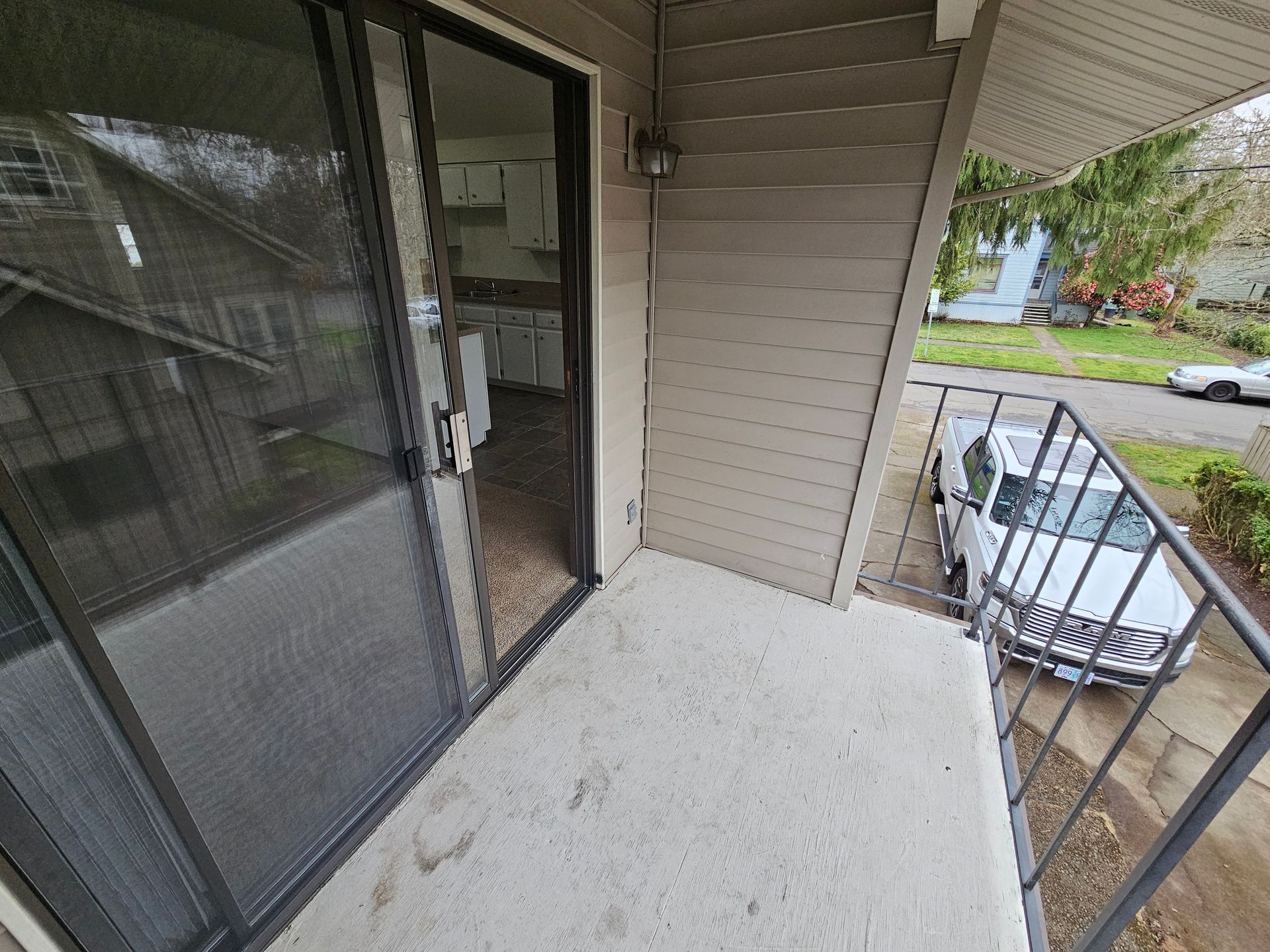 A balcony with a sliding glass door and a white truck parked in front of it.