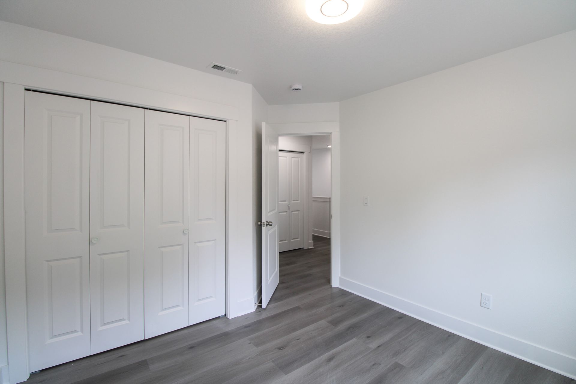 An empty bedroom with hardwood floors and white walls