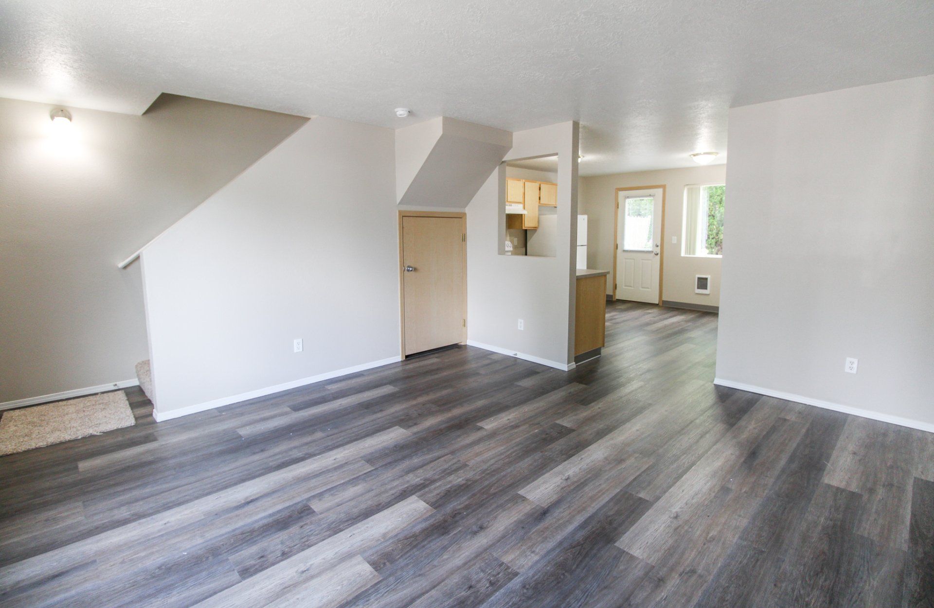 An empty living room with hardwood floors and white walls.