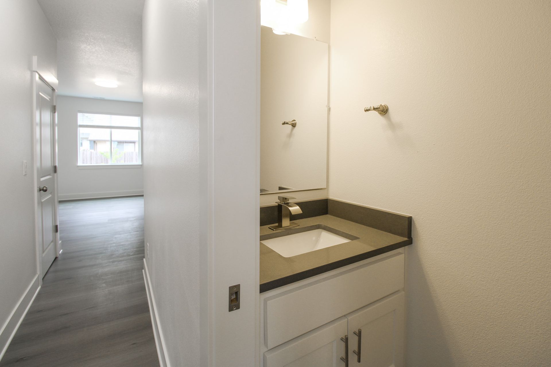 A bathroom with a sink and a mirror in a hallway.