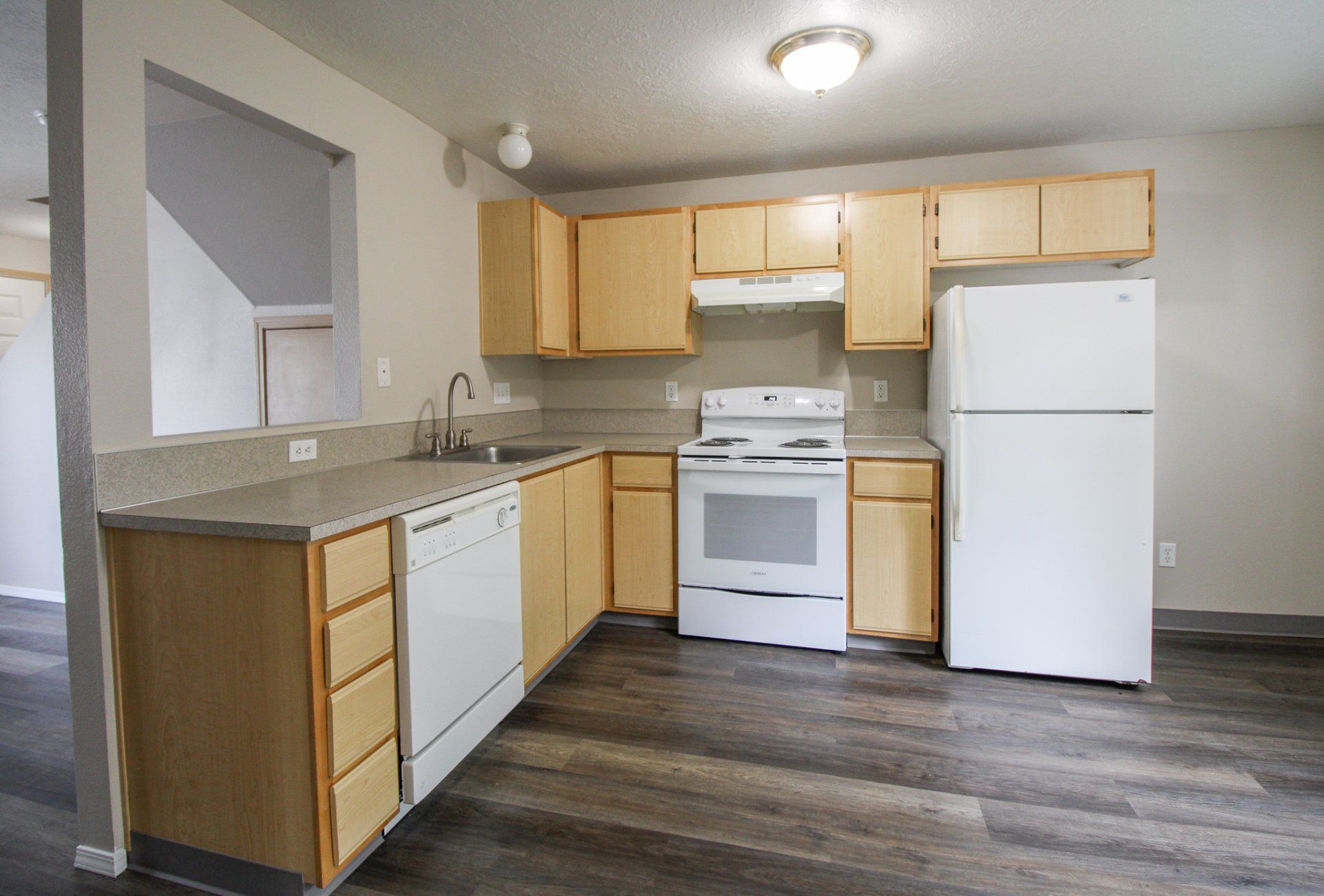An empty kitchen with wooden cabinets and a white refrigerator