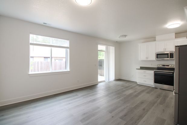 An empty living room with a sliding glass door leading to a kitchen.