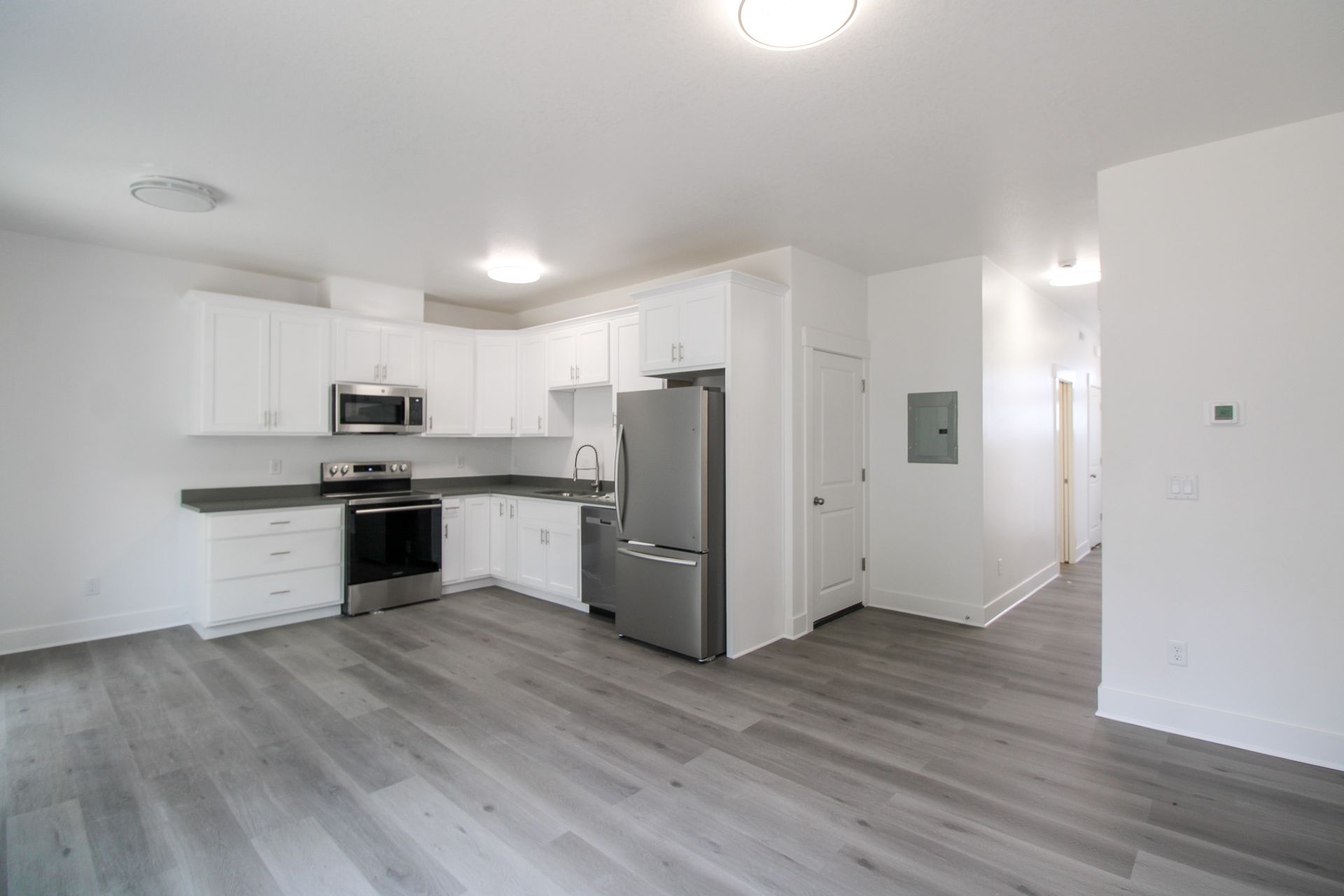 An empty kitchen with white cabinets and a stainless steel refrigerator.