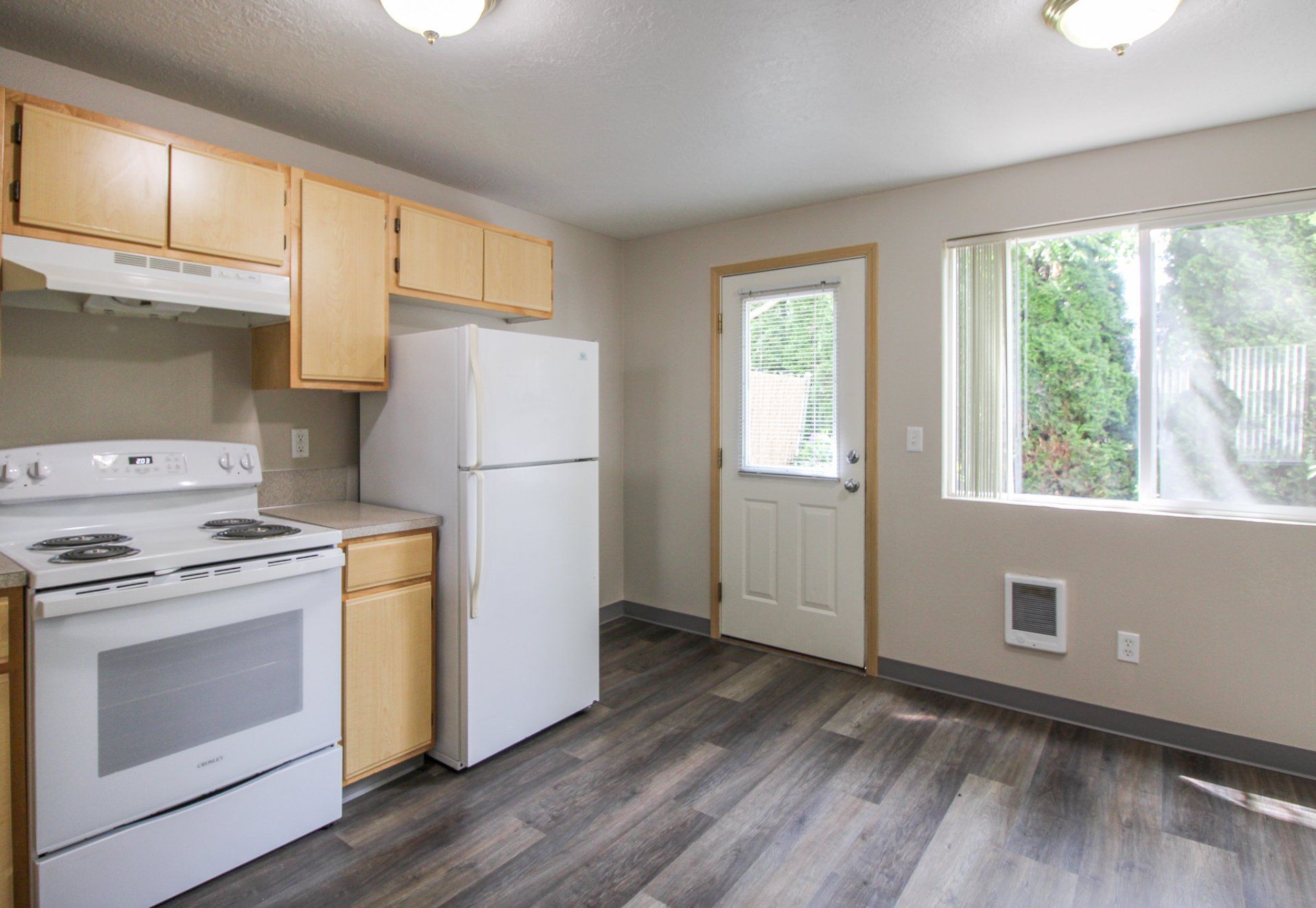 A kitchen with a stove , refrigerator , and a window.