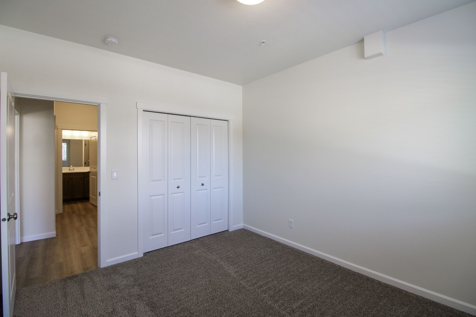 An empty bedroom with a closet and a carpeted floor.
