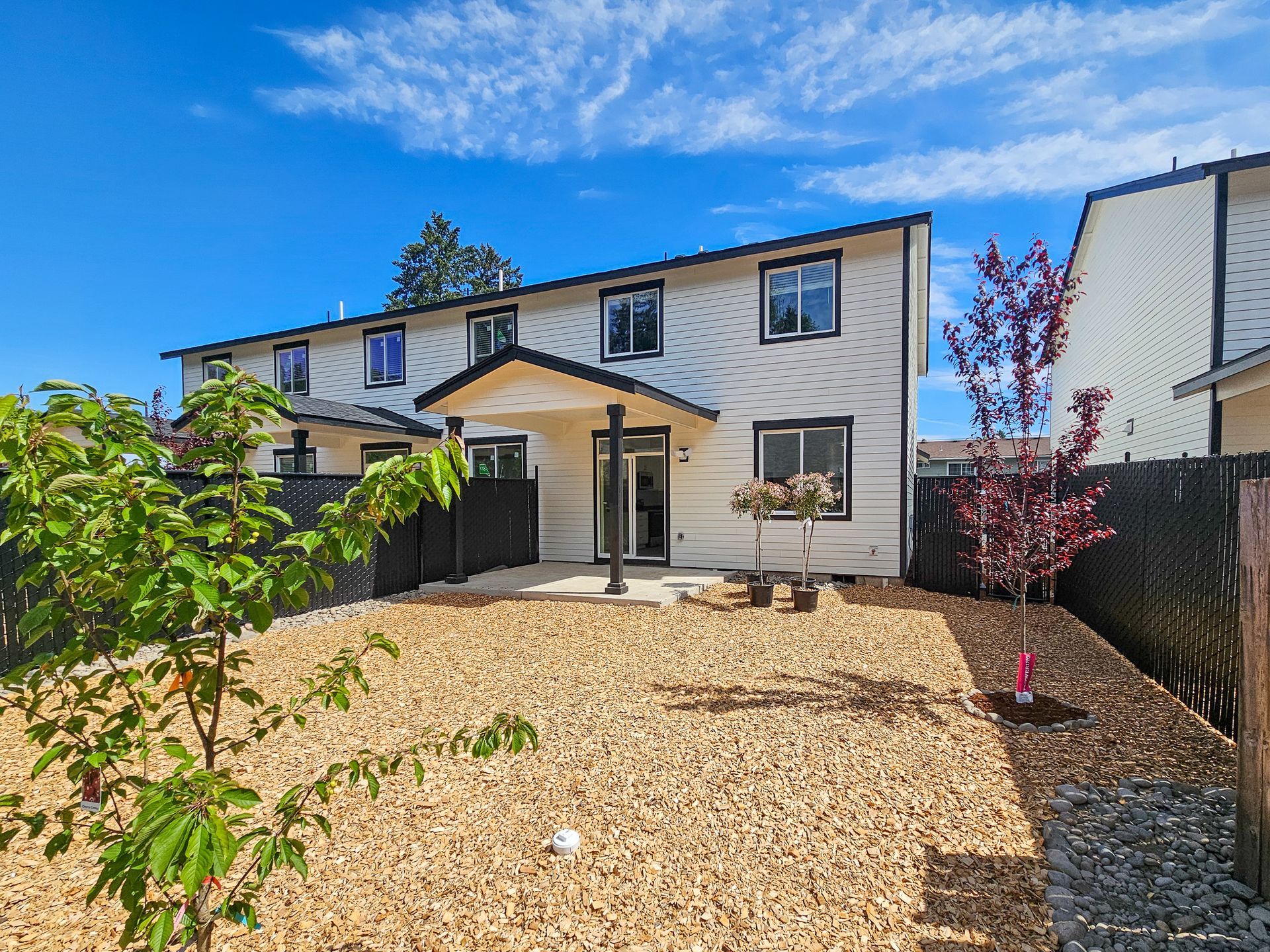 The backyard of a house with a lot of gravel and trees.