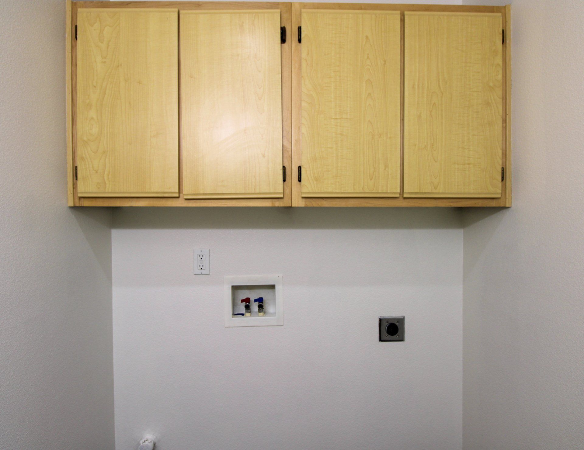 A laundry room with wooden cabinets above the washer and dryer.