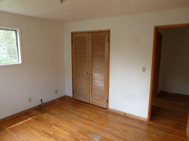 An empty room with hardwood floors and a window.
