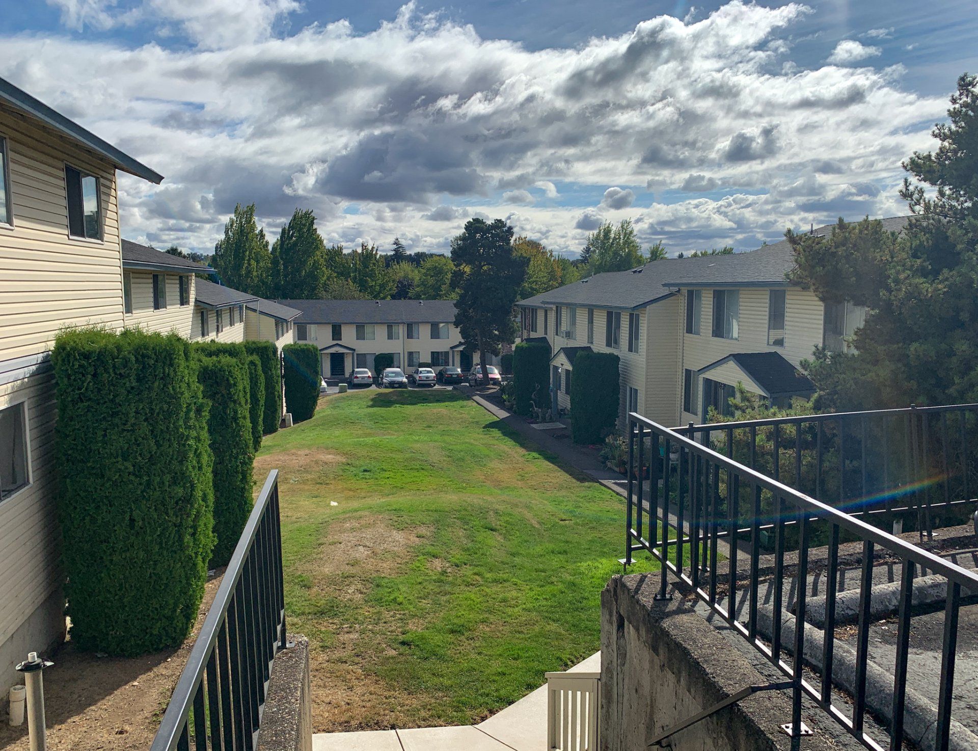 A row of apartment buildings with a lush green lawn in the middle.