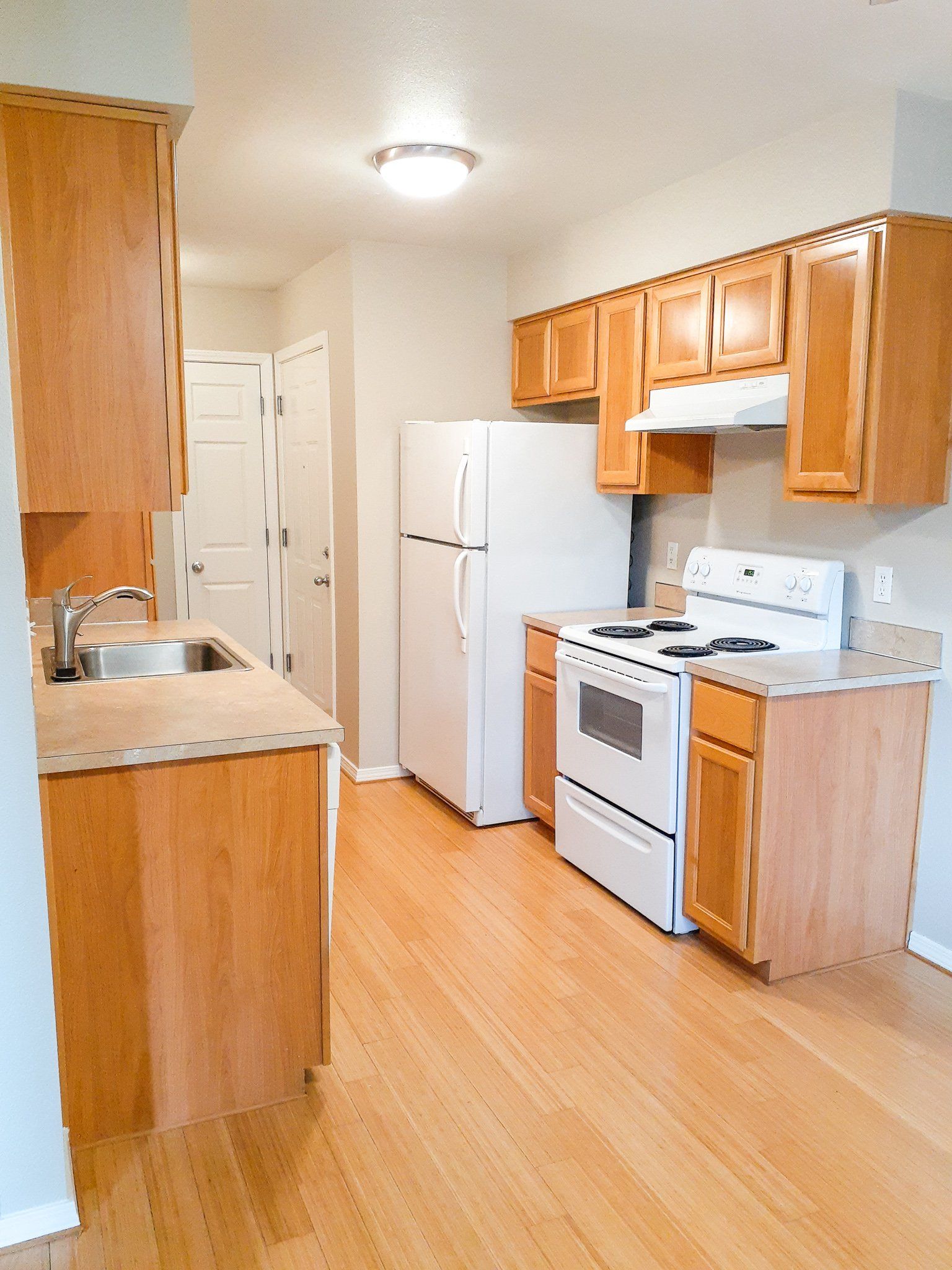 A kitchen with a stove , refrigerator , sink and cabinets