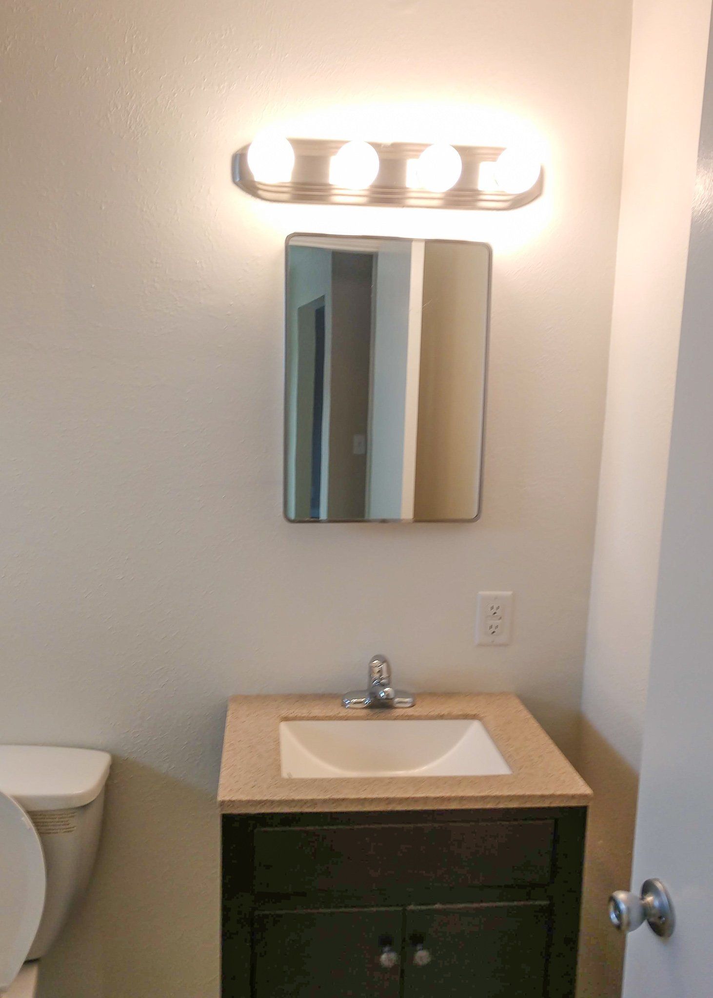 A bathroom with a sink , toilet and mirror.
