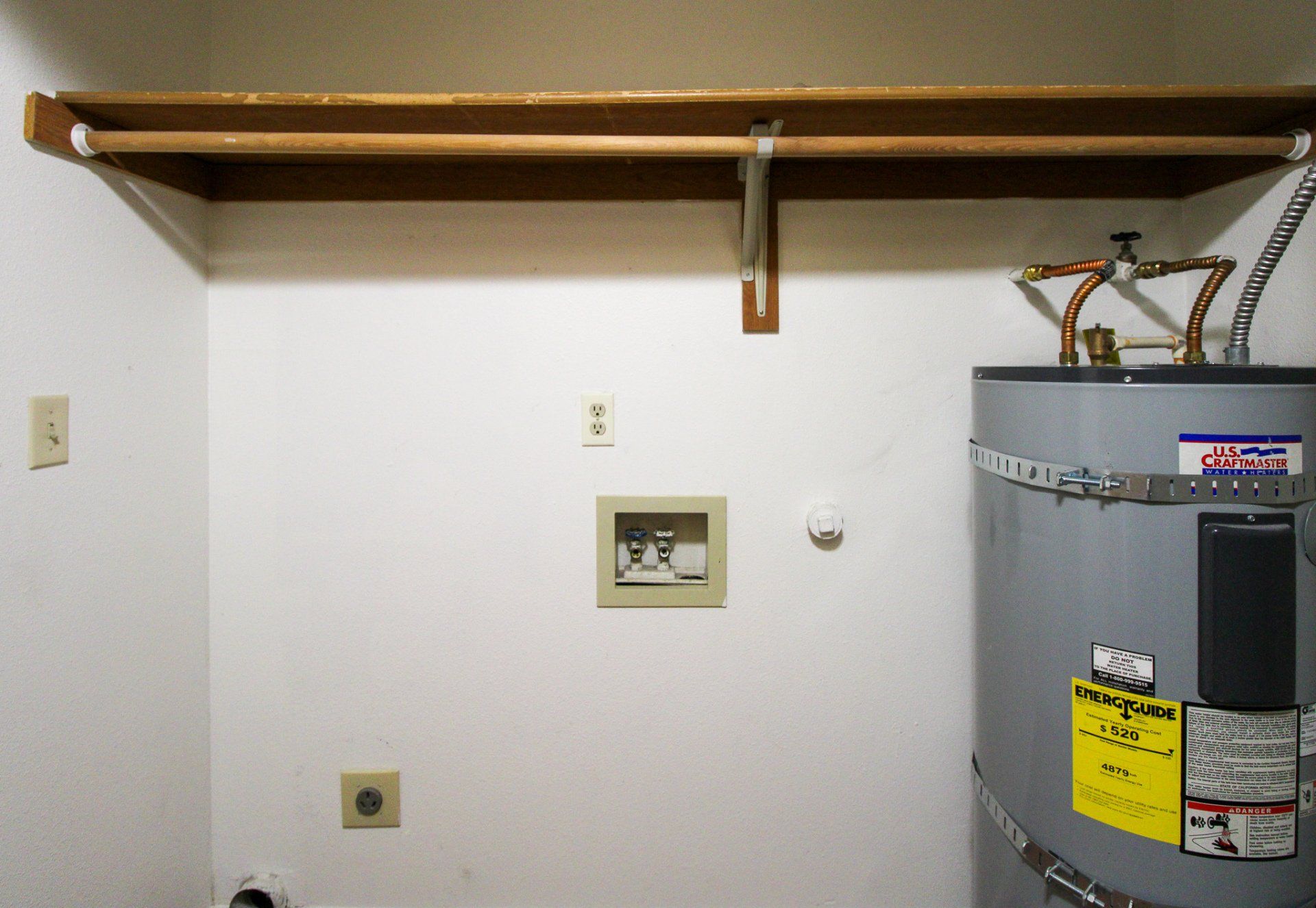 A laundry room with a water heater and a shelf