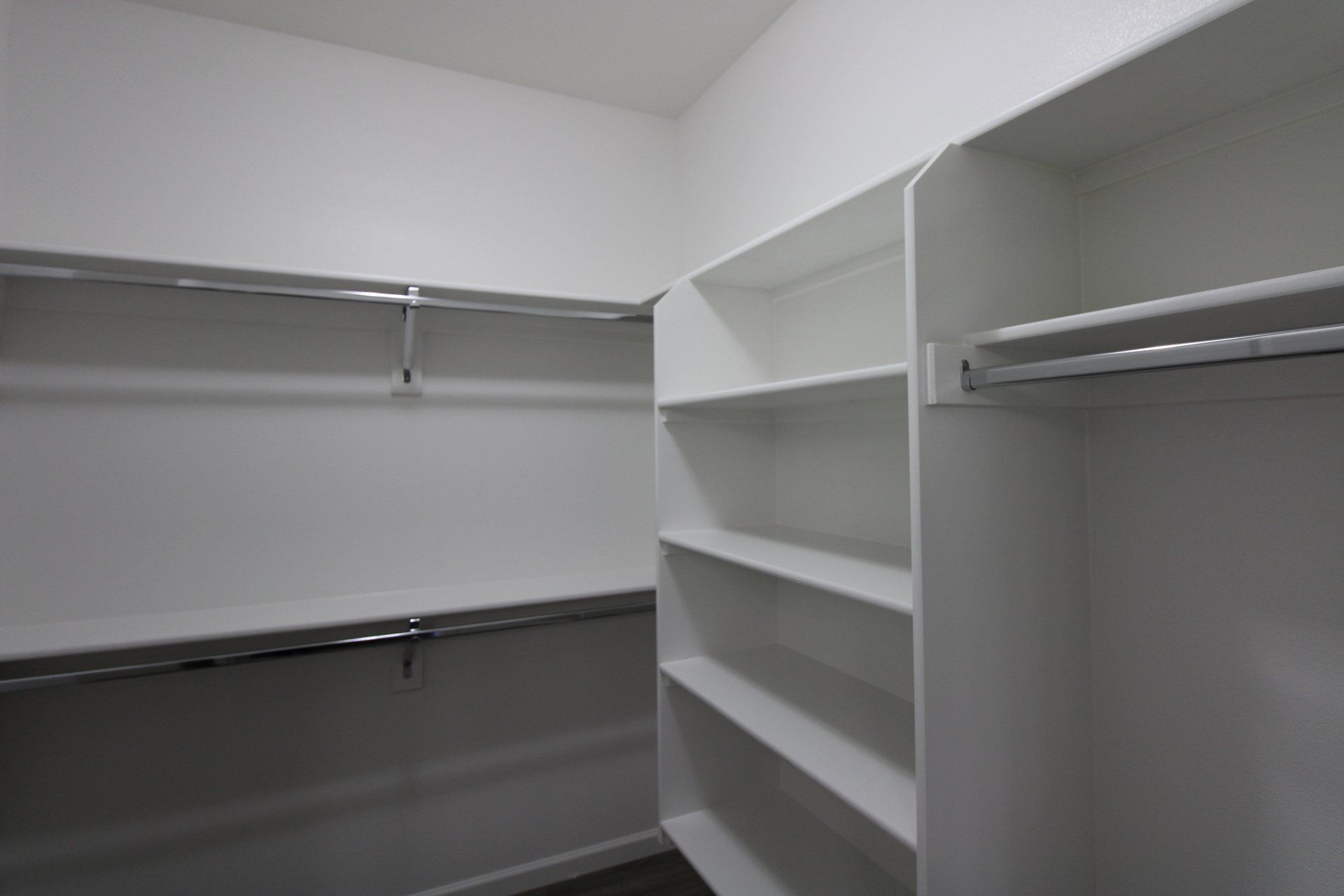 A walk in closet with lots of shelves and clothes racks.