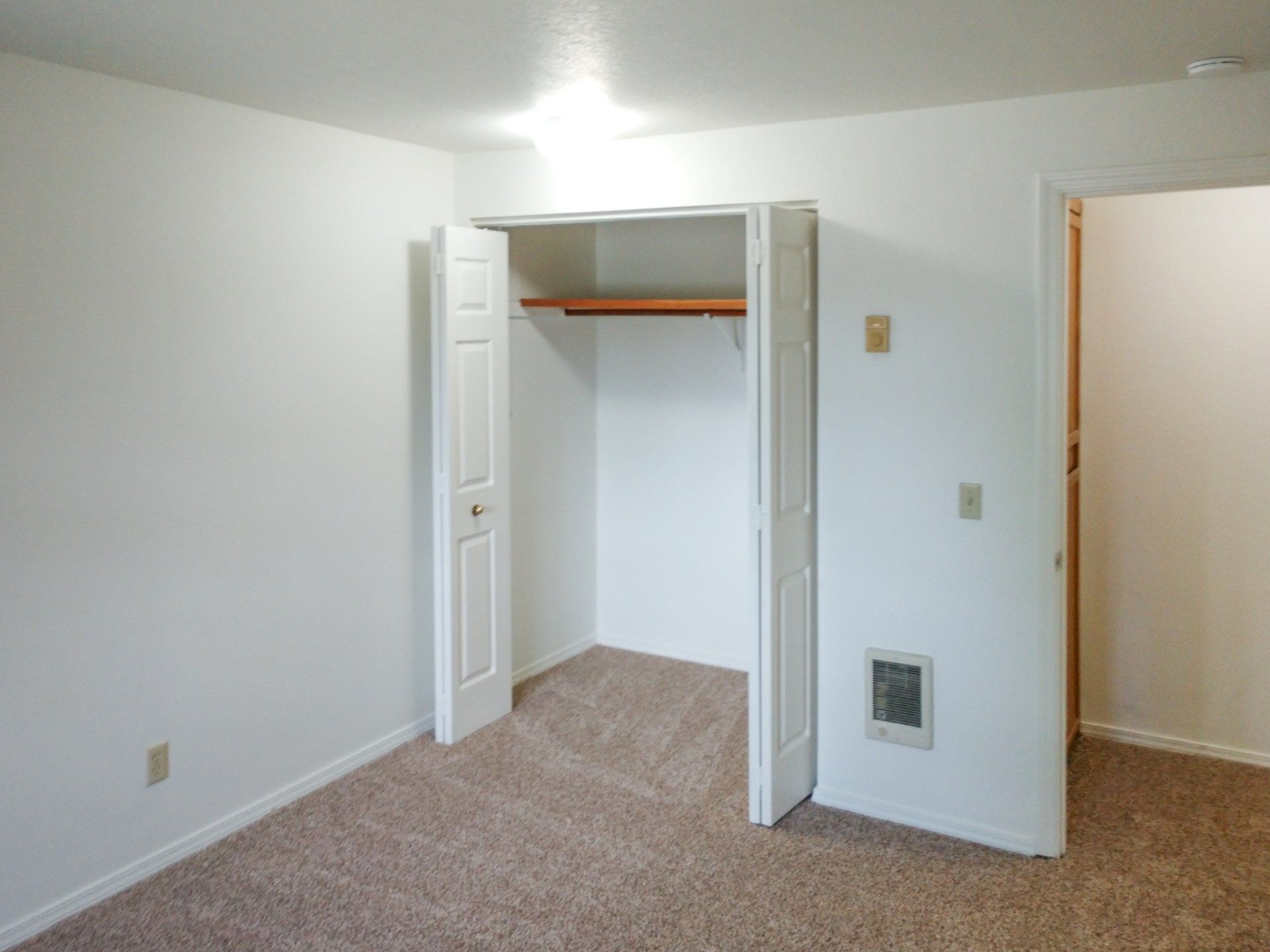 An empty bedroom with a closet and a carpeted floor.