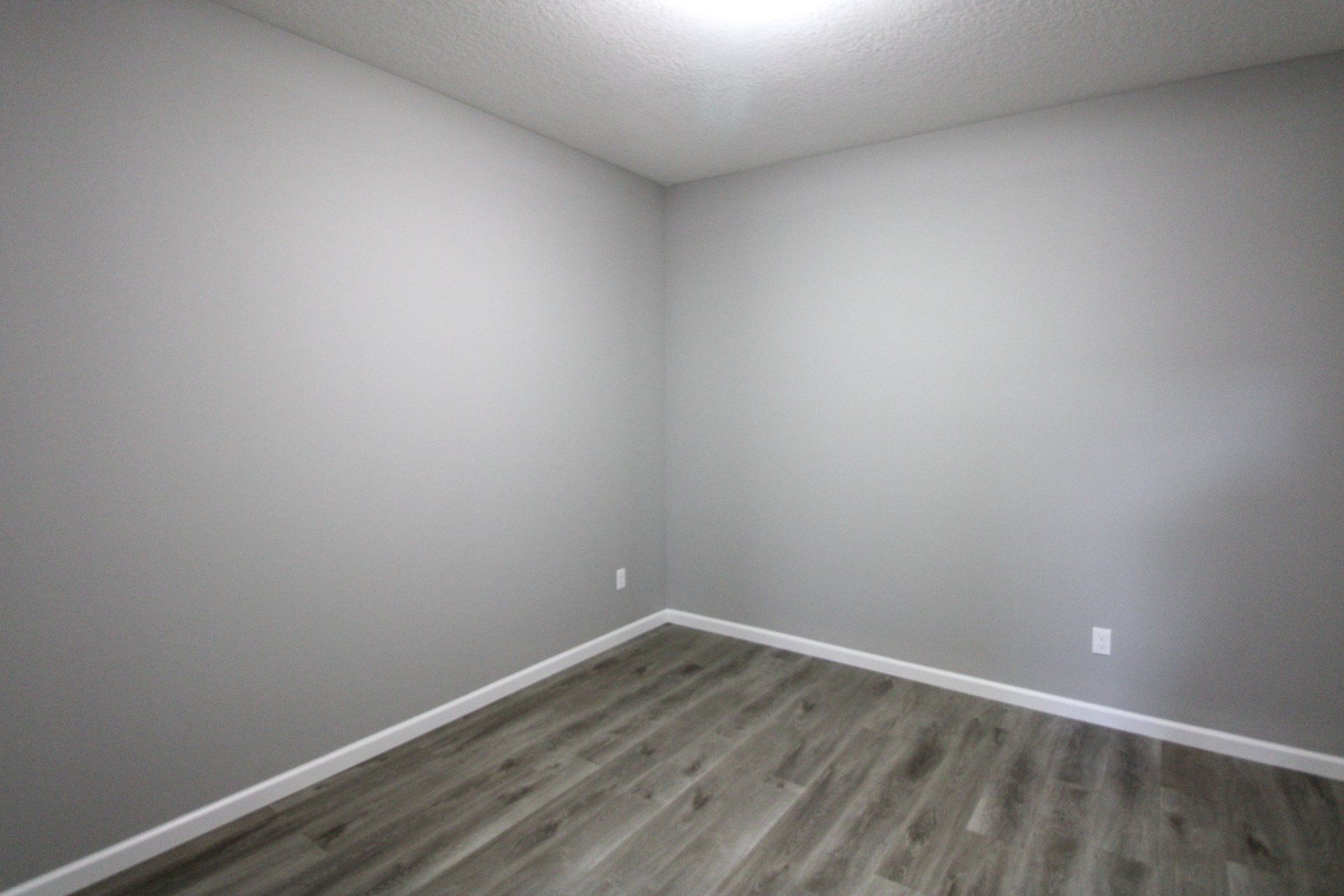 An empty room with gray walls and a wooden floor.