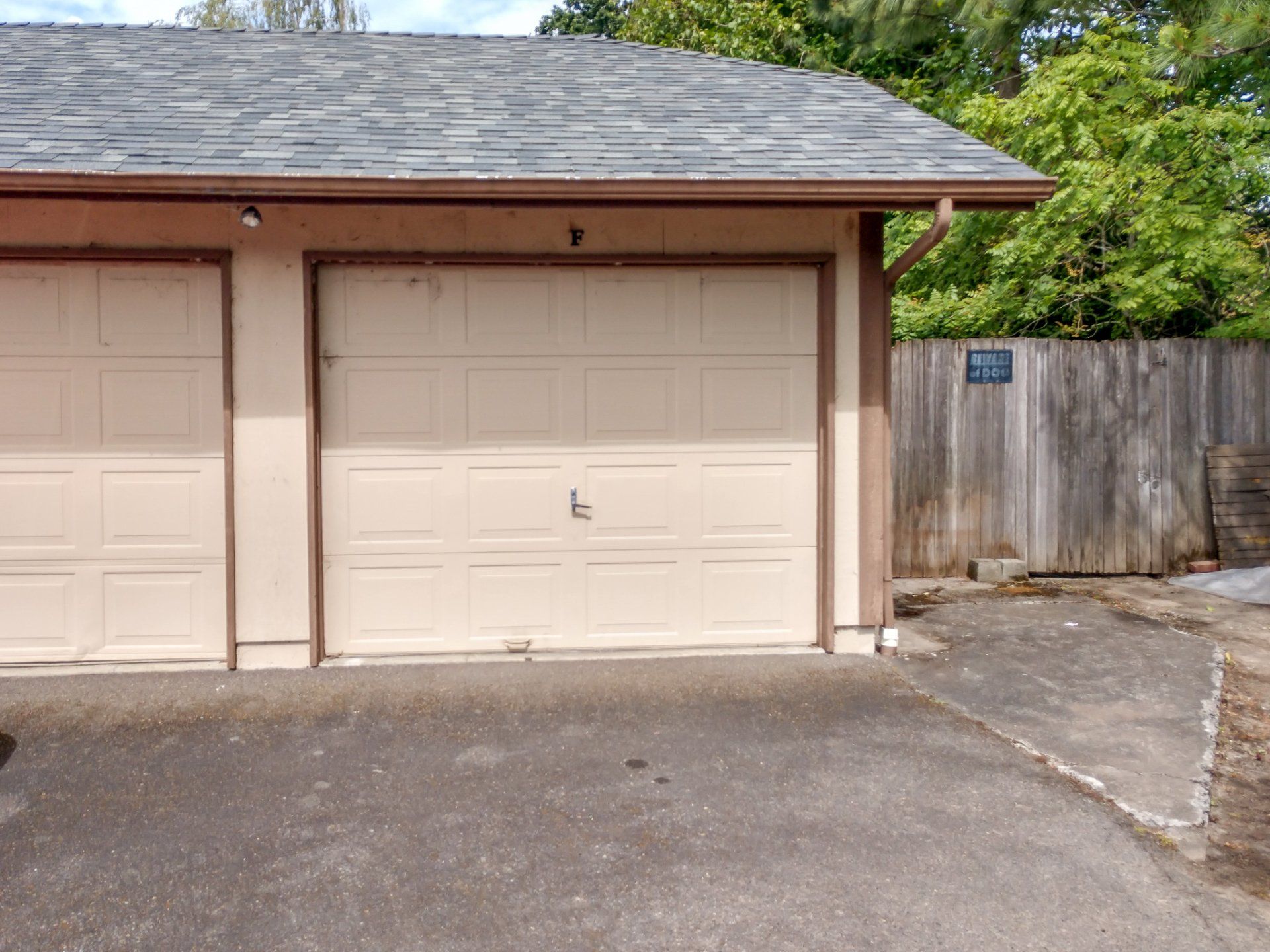 A garage with two doors and a wooden fence in the background