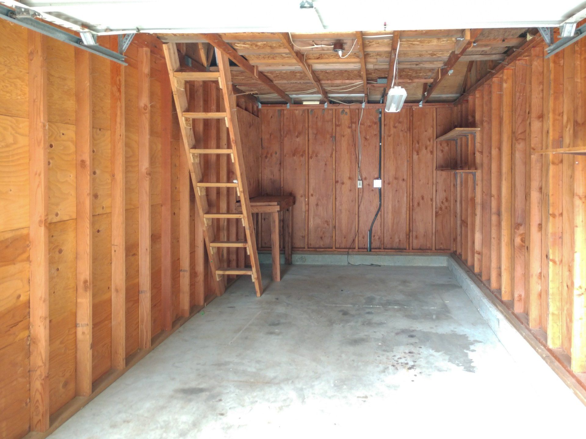 An empty garage with a ladder leading up to the second floor