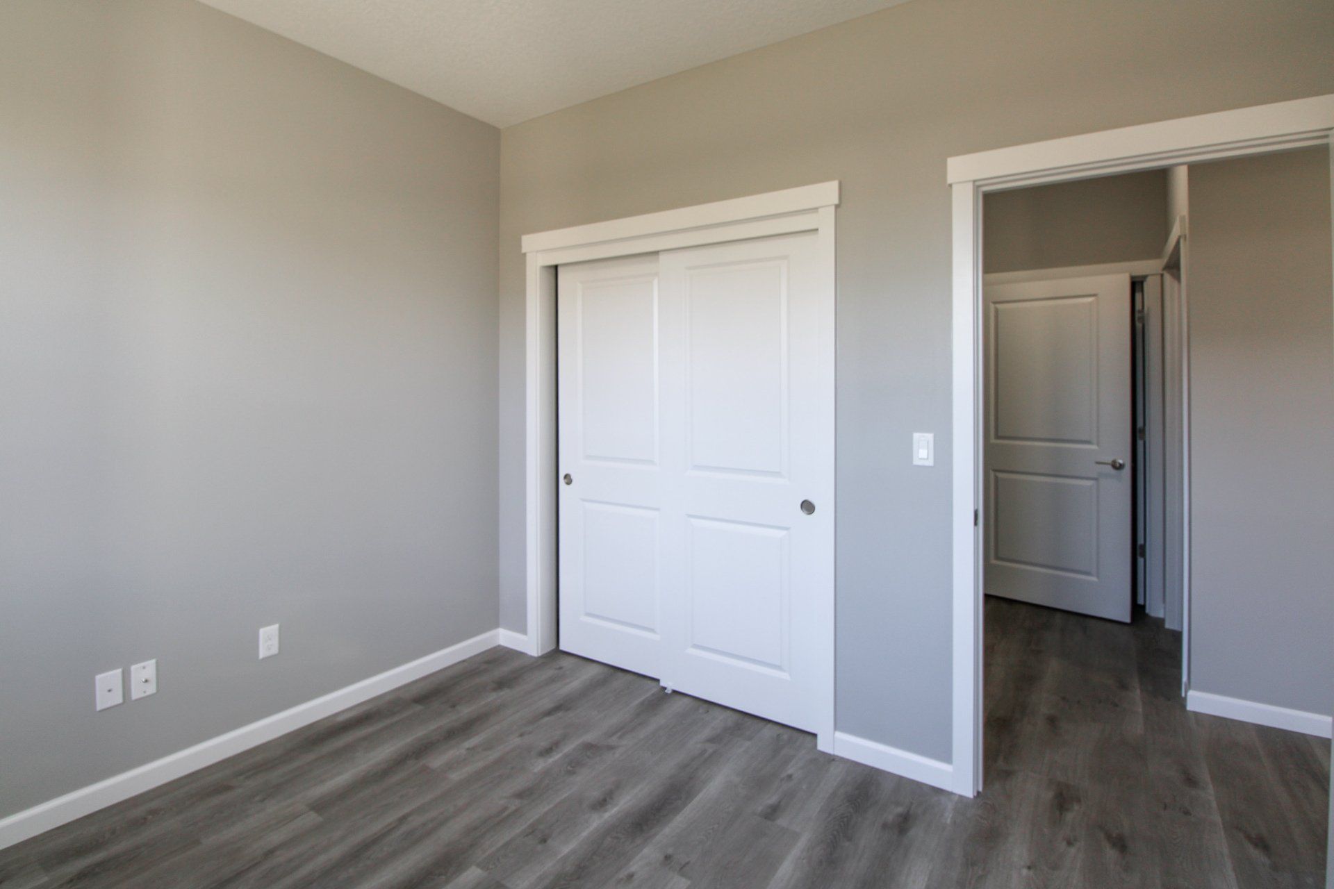 An empty bedroom with hardwood floors and a large closet.