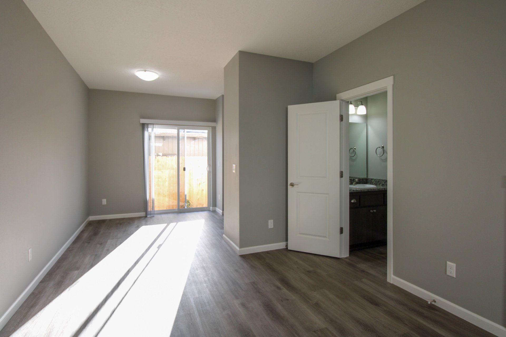 An empty room with a sliding glass door and a bathroom.
