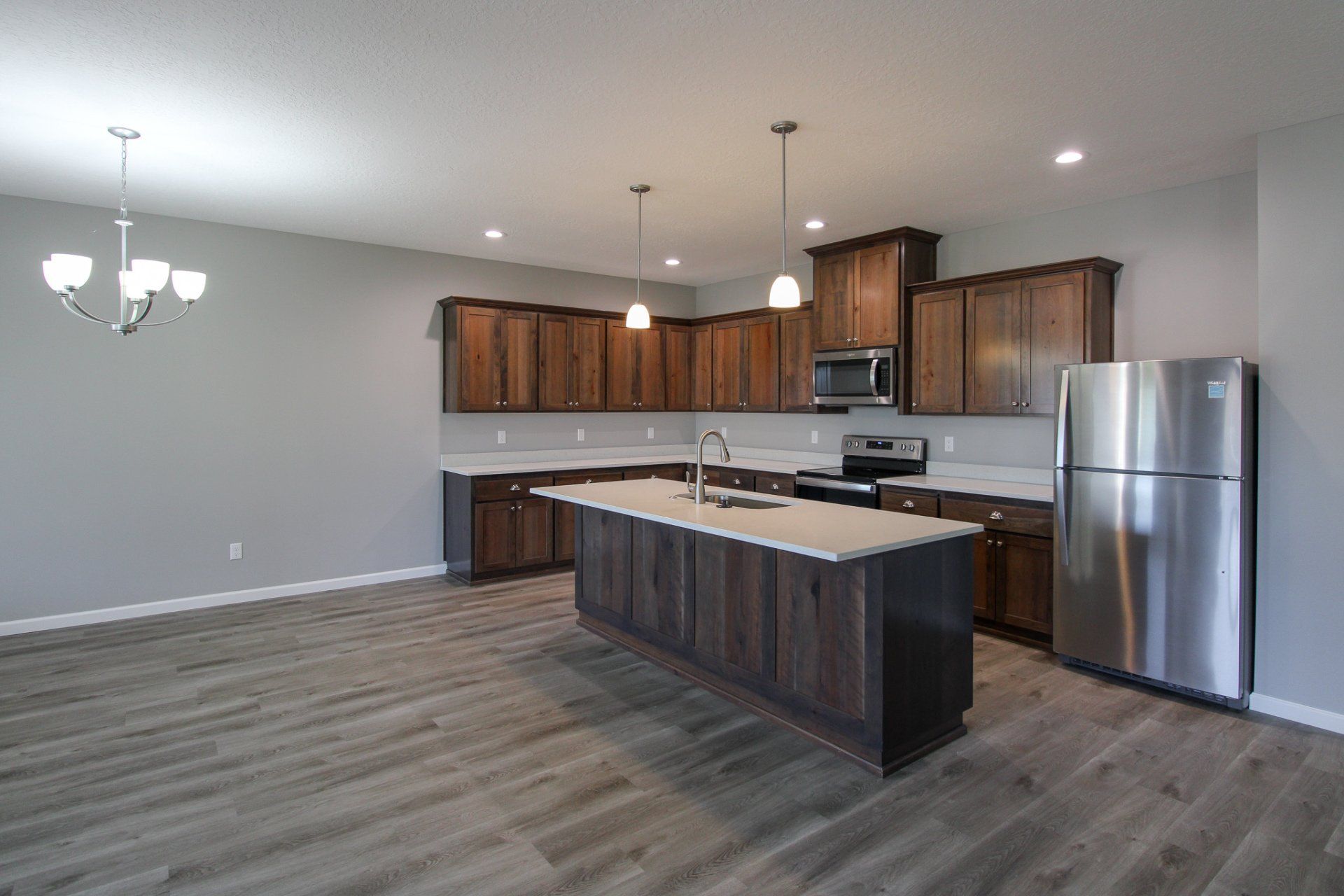 An empty kitchen with stainless steel appliances and wooden cabinets.