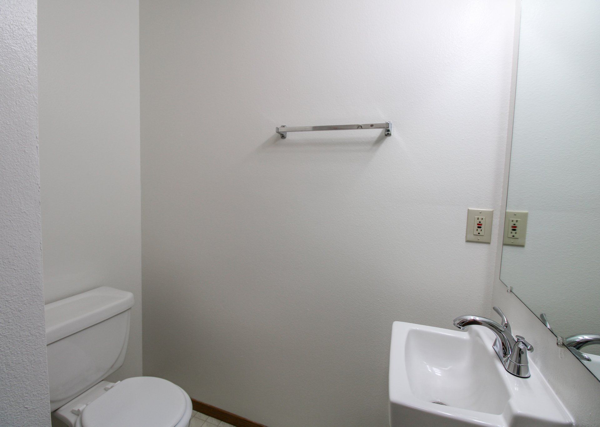 A bathroom with a toilet a sink and a mirror