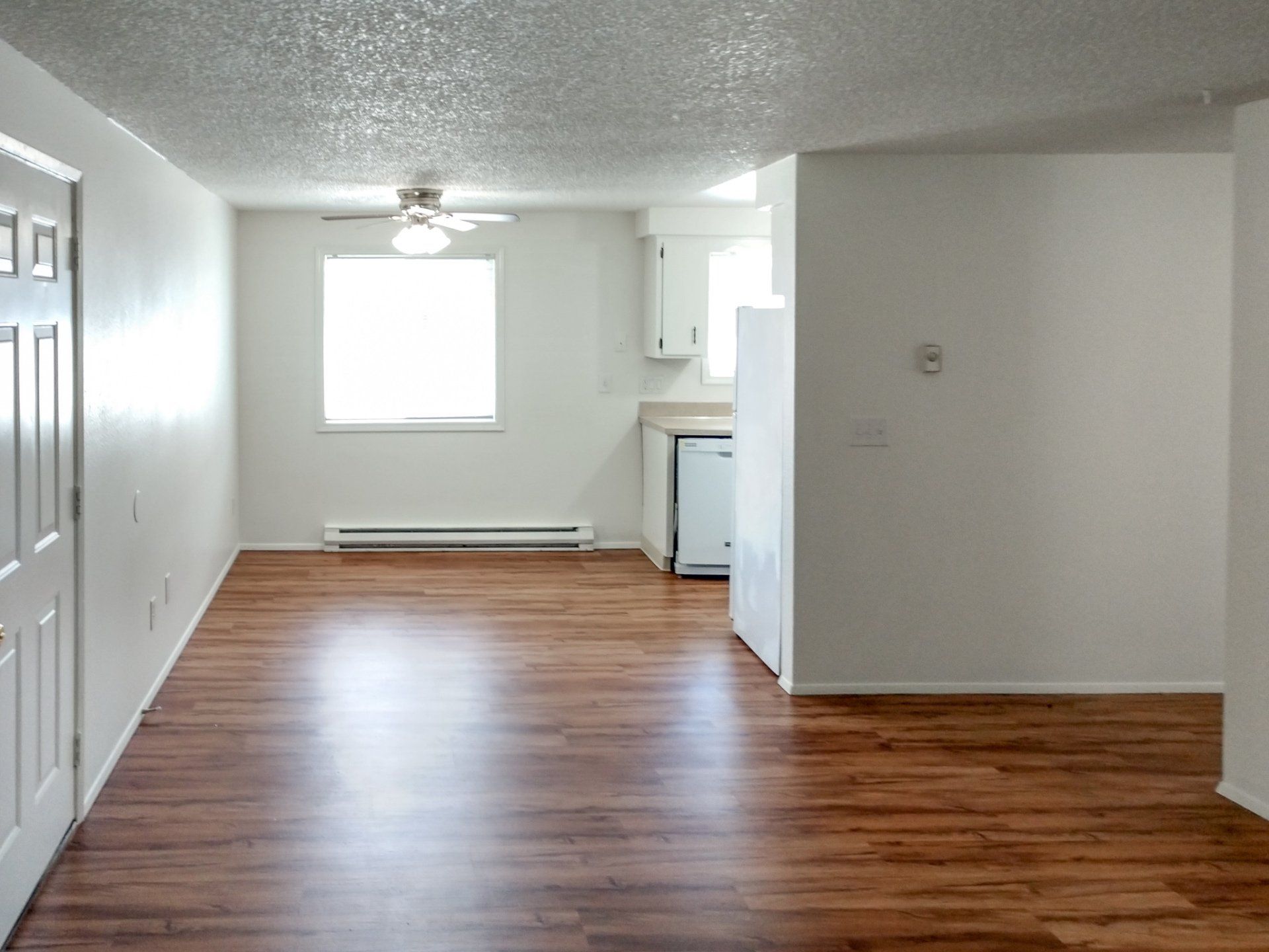 An empty room with hardwood floors and white walls