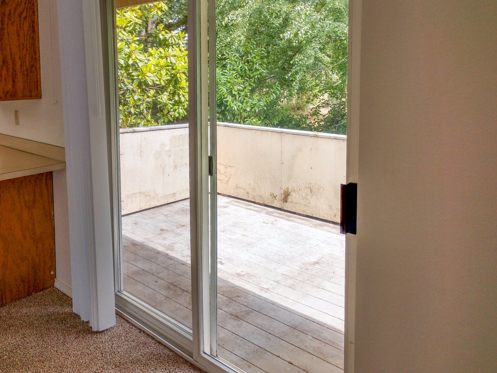 An empty room with a sliding glass door leading to a deck.